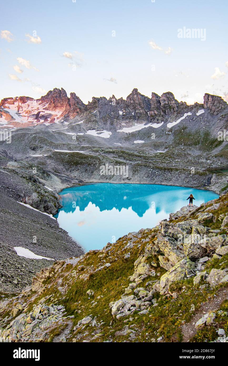 Abenteuerlicher Mann, der auf einer Klippe mit Blick auf die wunderschönen Schweizer Rockies und den Wildsee bei einem lebhaften Sonnenuntergang steht. Aufgenommen in den Schweizer Alpen, Schweiz Stockfoto