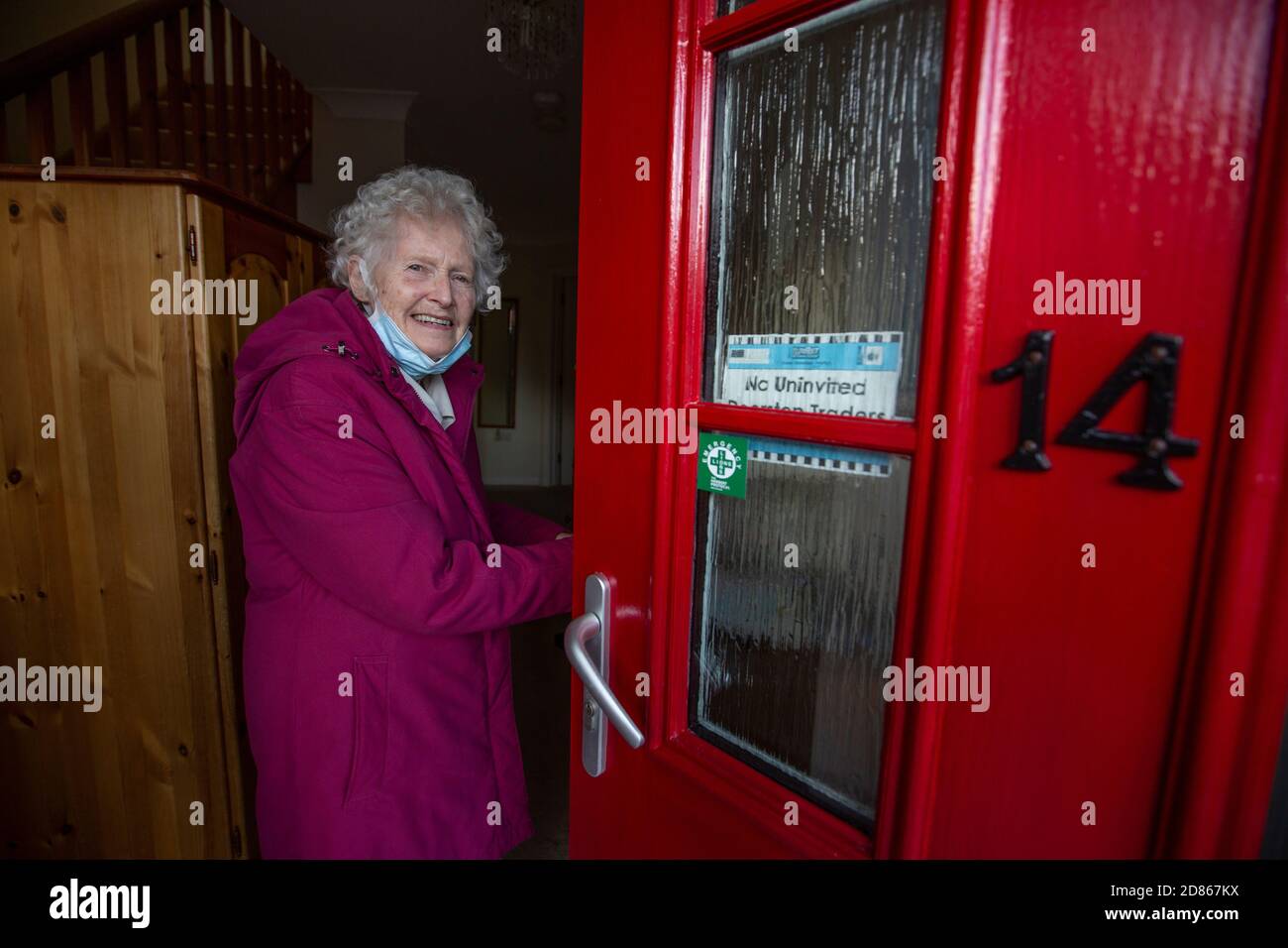 Ältere Frau in den 80ern stand in der Tür zu ihrem Haus, Südwestengland, Großbritannien Stockfoto