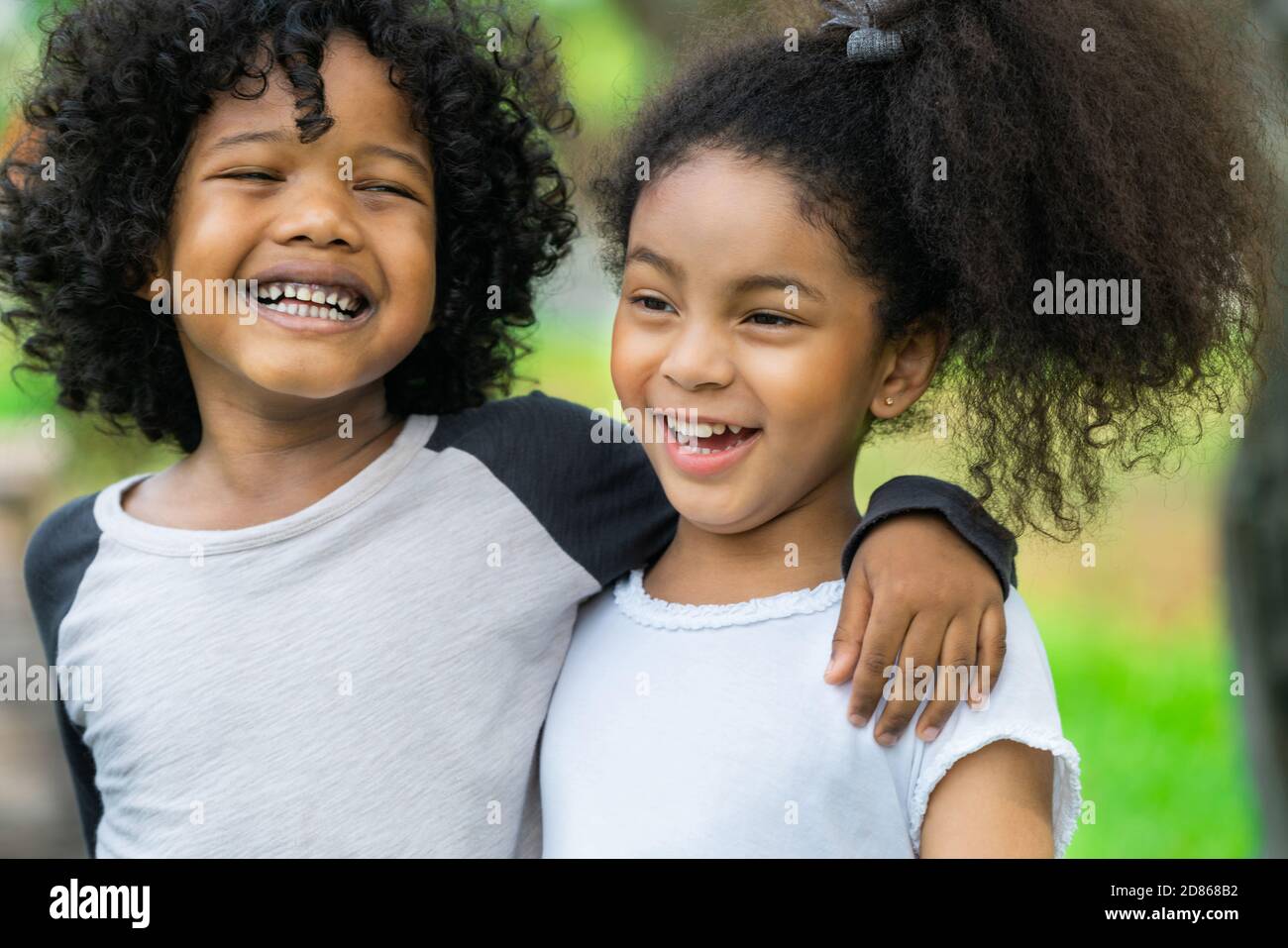 Glückliche kleine Jungen und Mädchen im Park. Zwei afrikanische amerikanische Kinder zusammen in den Garten. Stockfoto