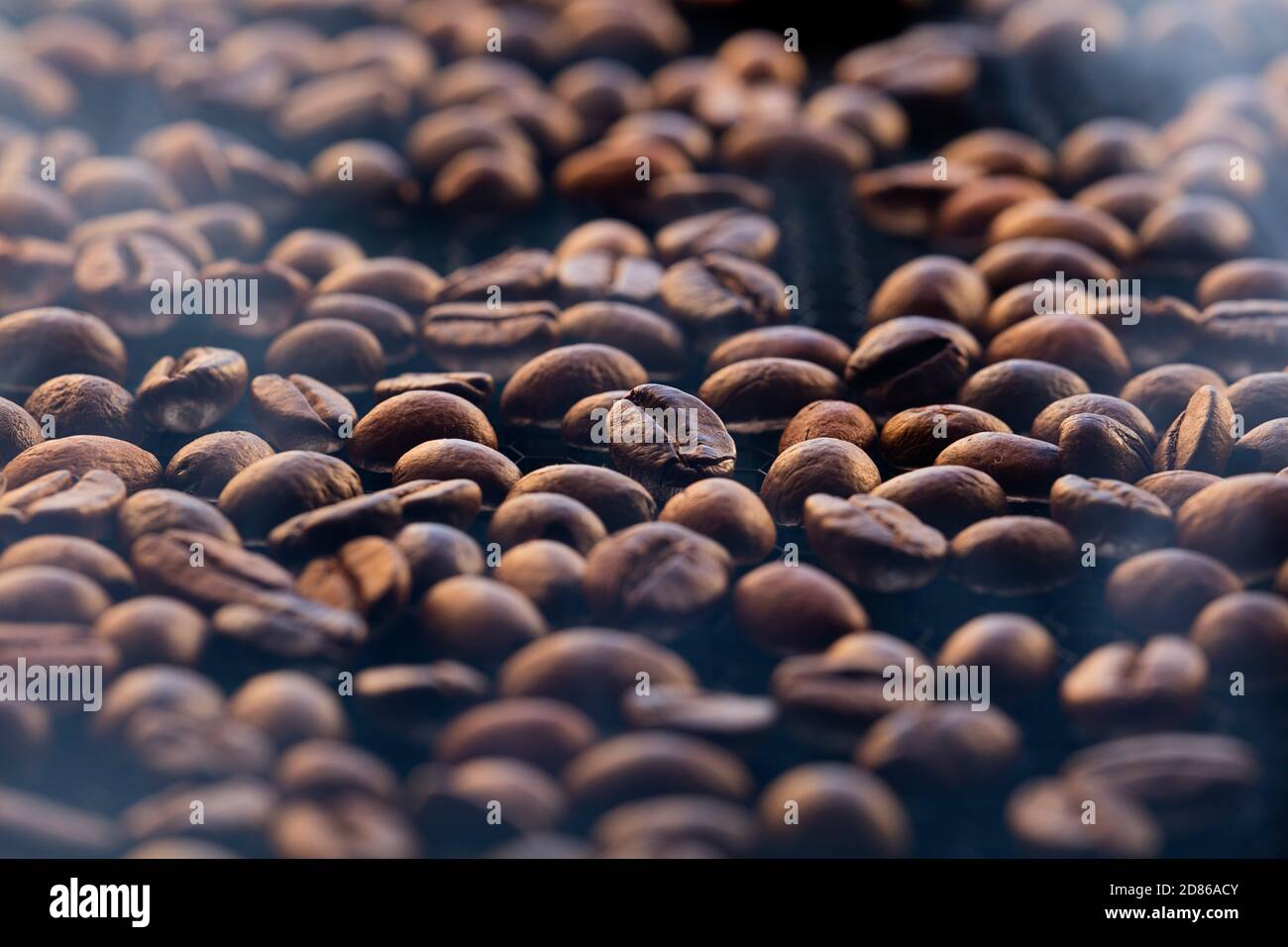 Gebrochene Kaffeebohnen, Hintergrund der Röstung Kaffeebohnen mit Rauch. Stockfoto