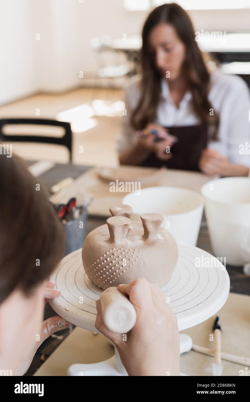Kind in den Prozess der Dekoration der Tonvase. Töpferwerkstatt für Kinder. Stockfoto