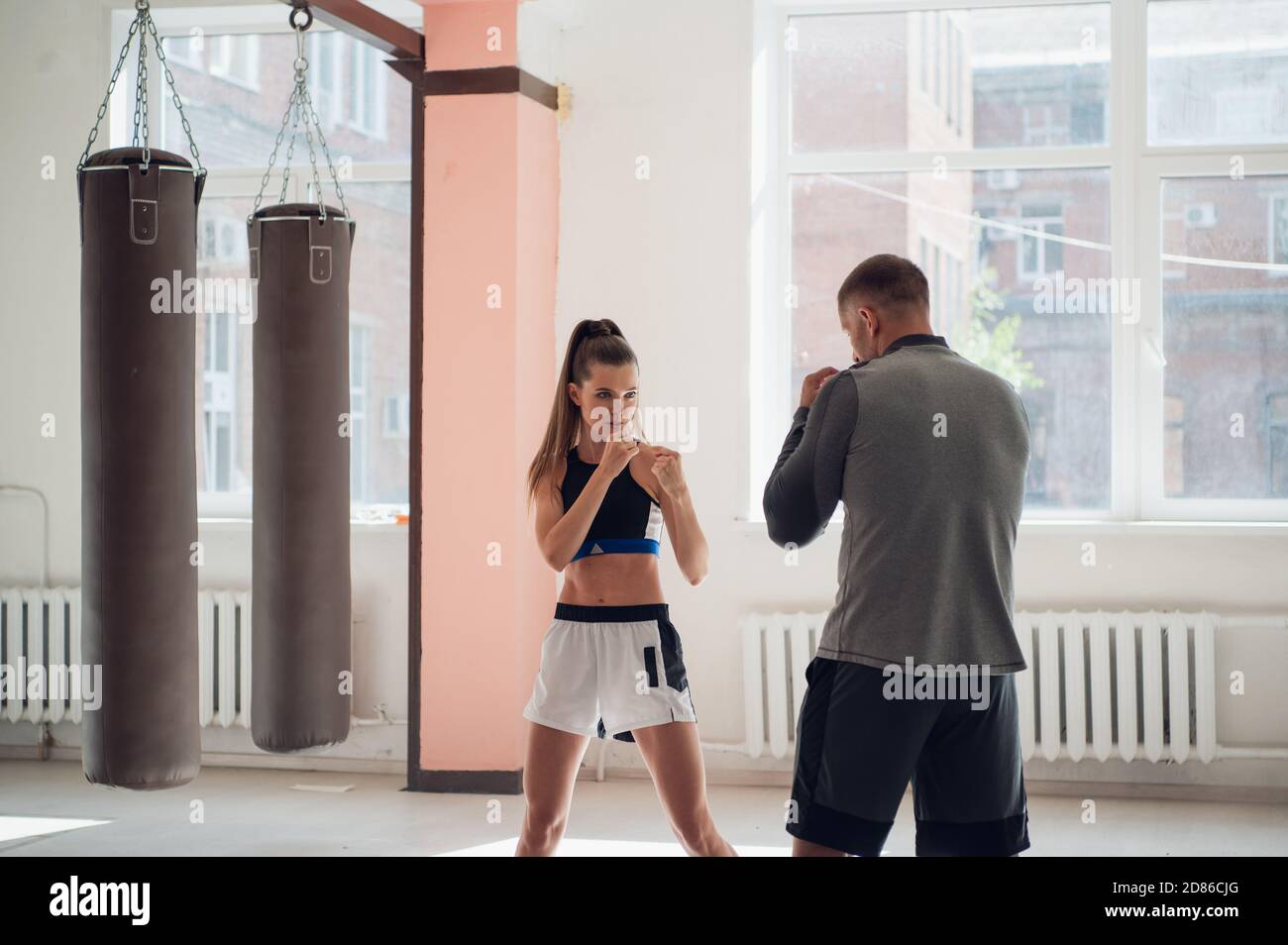 Das erste Training einer jungen Kämpferin im Kickboxen zeigt der Trainer die Schläge Stockfoto