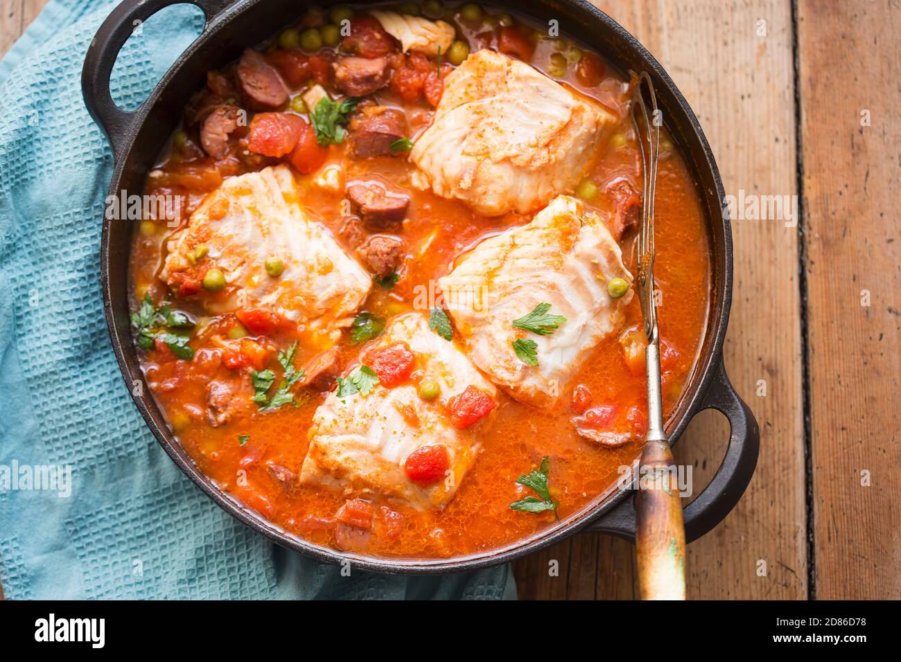 Kabeljau-Chorizo-Eintopf mit Erbsen und Petersilie in Tomatensauce Stockfoto