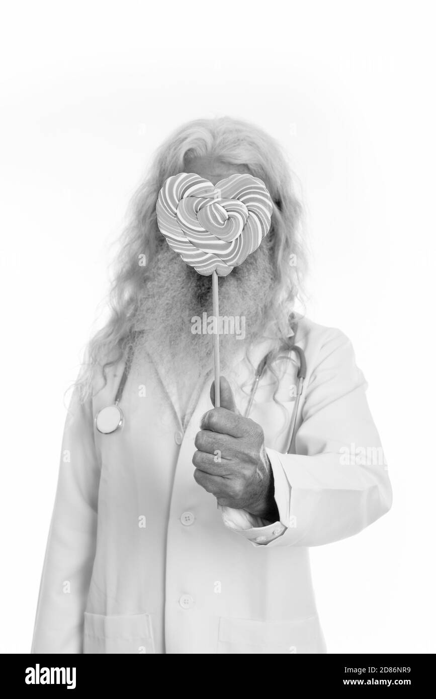Studio shot der älteren bärtigen Mann Arzt für Gesicht mit köstlichen Herzförmige bunte Spirale lollipop Stockfoto