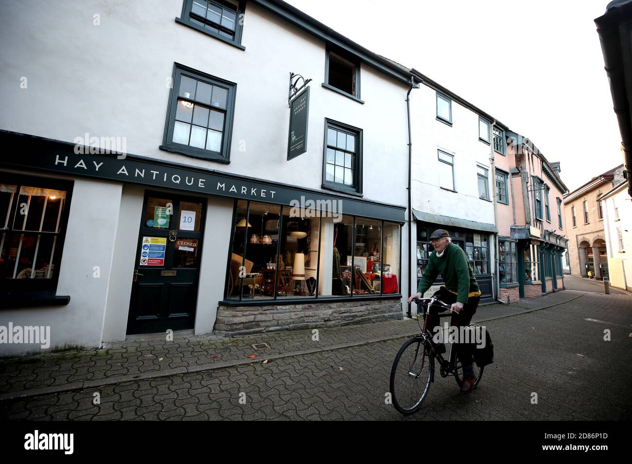 Ein Mann radelt an geschlossenen Geschäften in Hay-on-Wye vorbei. Wales steht unter einem zweiwöchigen "Feuerbruch"-Lockdown, um den NHS des Landes vor dem Wiederaufleben des Coronavirus zu schützen. Stockfoto