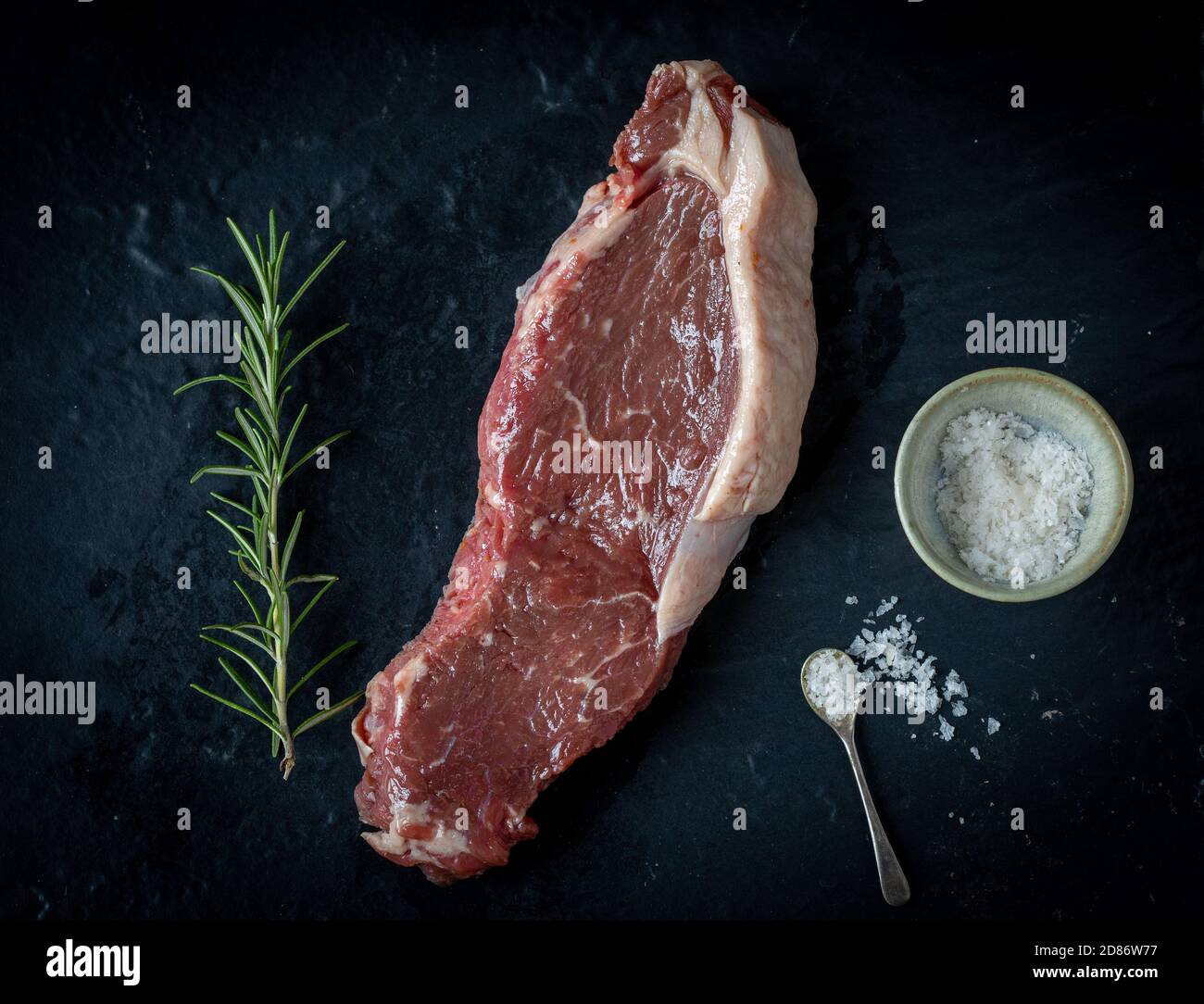 Rohes Fleisch auf Schiefer mit Rosmarin und Salz Stockfoto