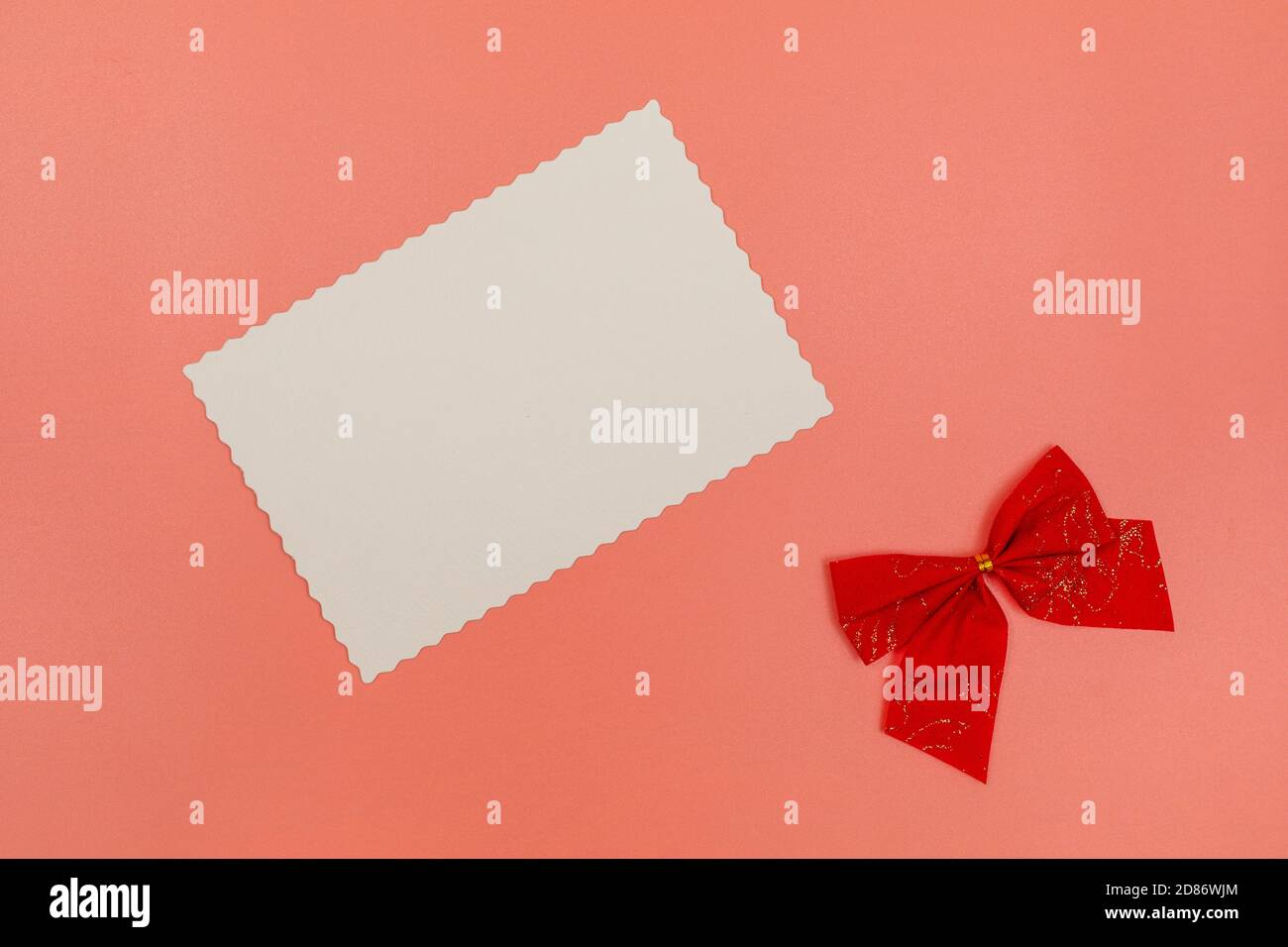 Weiße Postkarte und rote Schleife Dekoration auf rosa Hintergrund. Weihnachten, Neujahr, Valentinstag, Internationaler Frauentag oder Muttertag Stockfoto