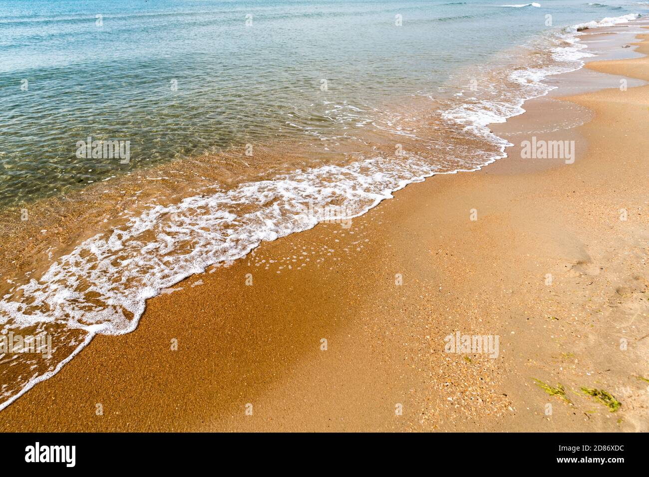 Wellen mit Meeresschaum an einem Sandstrand Stockfoto