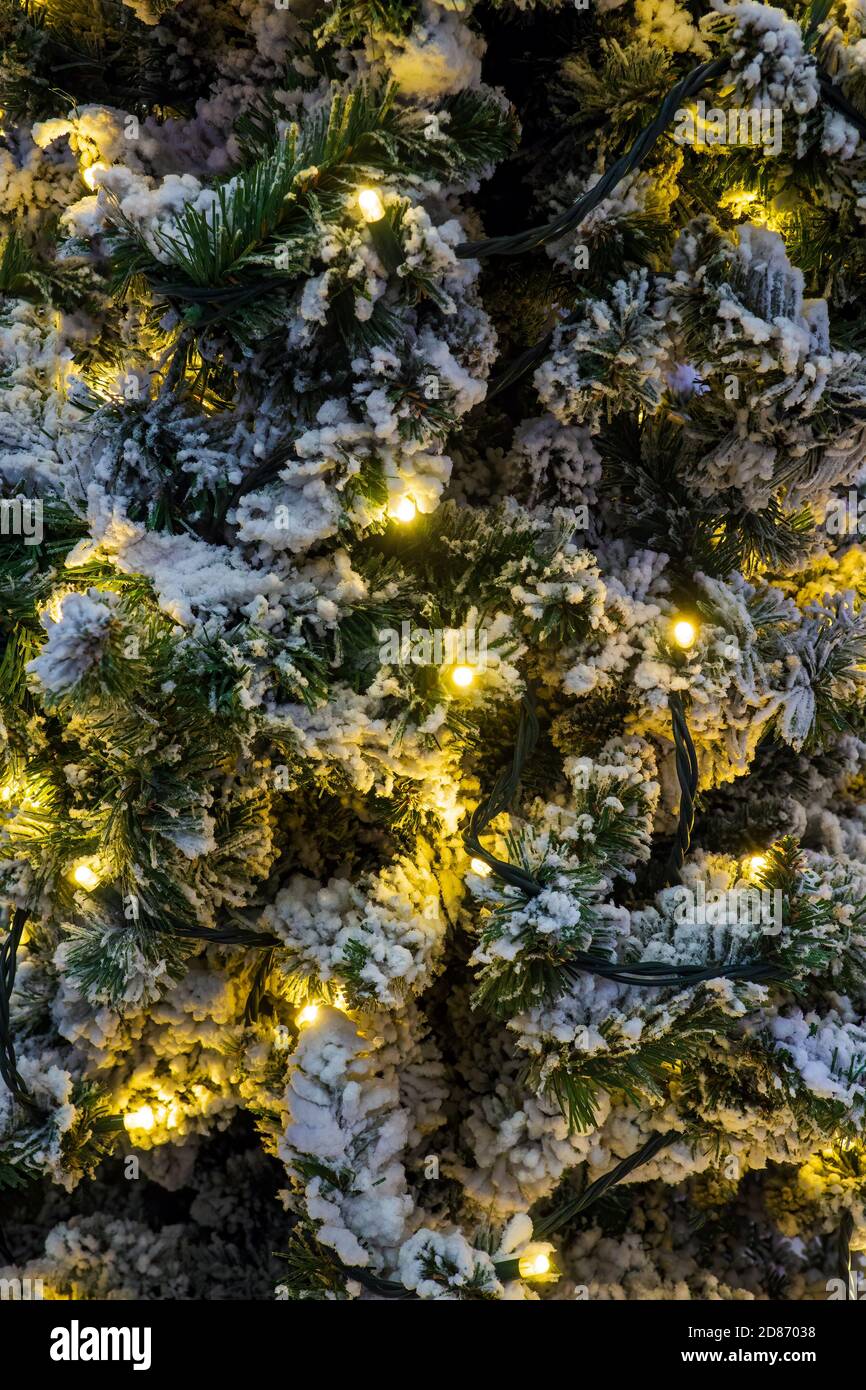 Hintergrund eines Weihnachtsbaums und künstlicher Schnee mit einer Girlande. Winter Weihnachten vertikale Muster Stockfoto