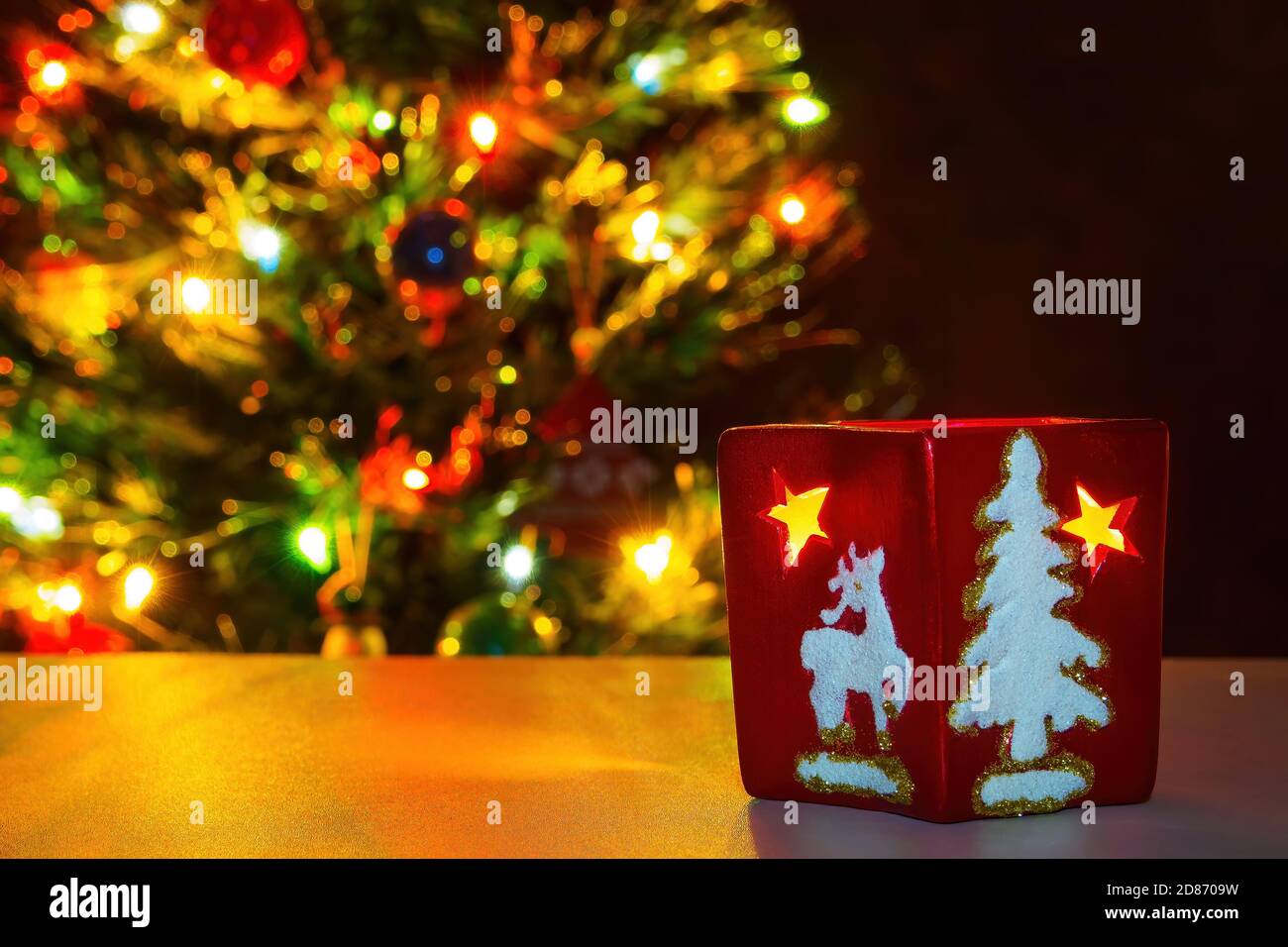 Rote weihnachtsschale mit Sternen und Ornamenten auf verschwommenem Hintergrund von Girlande Lichter. Text kopieren, selektiver Fokus Stockfoto