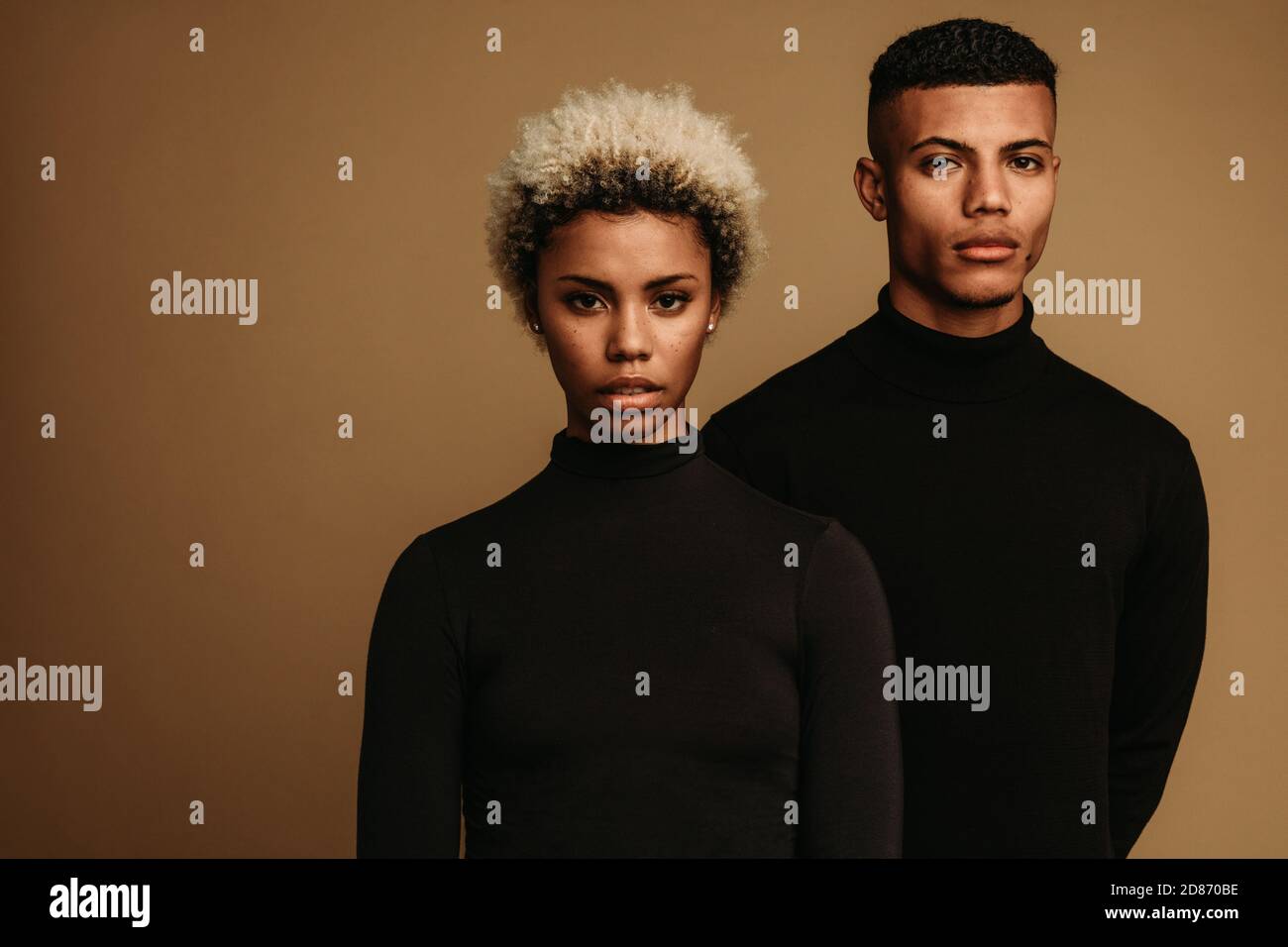 Nahaufnahme von ernsthaft aussehenden afroamerikanischen Mann und Frau. afroamerikanisches Paar auf braunem Hintergrund in schwarzer Kleidung. Stockfoto