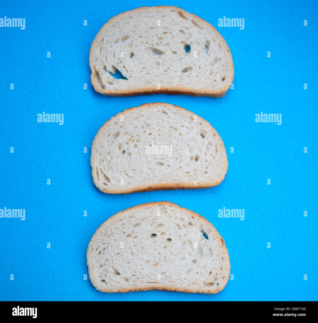 Drei Scheiben Weizenbrot auf blauem Hintergrund Stockfoto