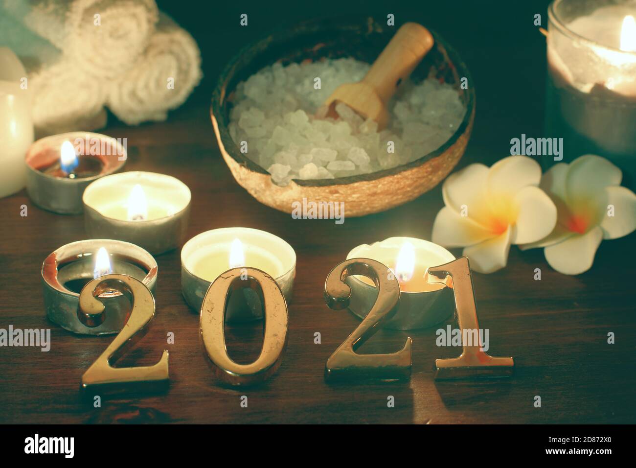 Ein Set für Spa-Behandlungen und brennende Kerzen neben den Nummern 2021. Stockfoto