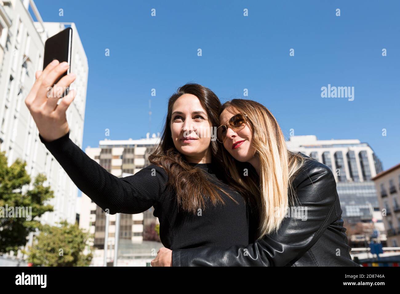 Zwei Mädchen umarmen und machen ein Selfie in der Stadt. Stockfoto