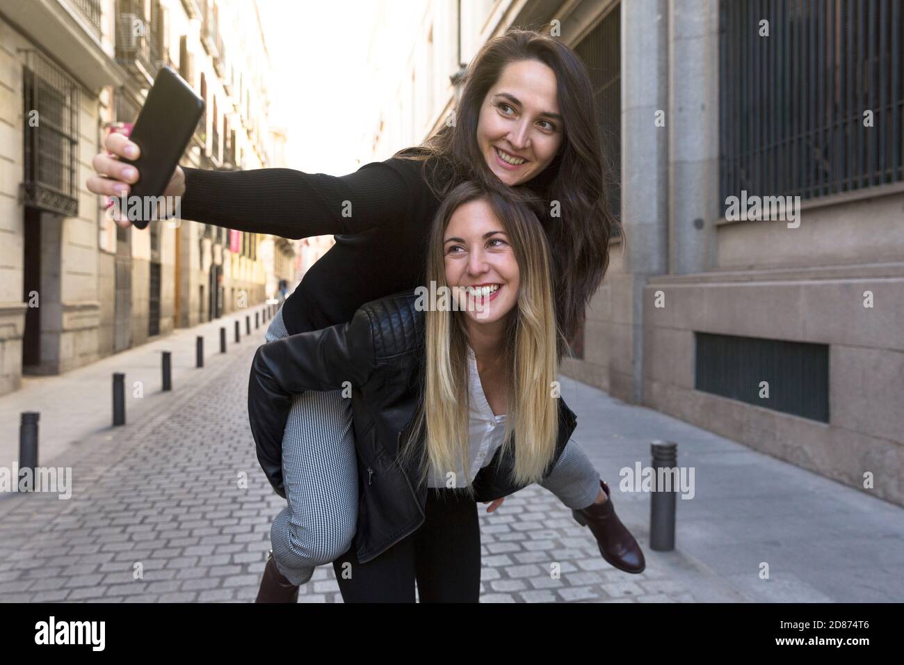 Zwei lustige Mädchen, die ein Selfie auf einer Stadtstraße machen. Stockfoto