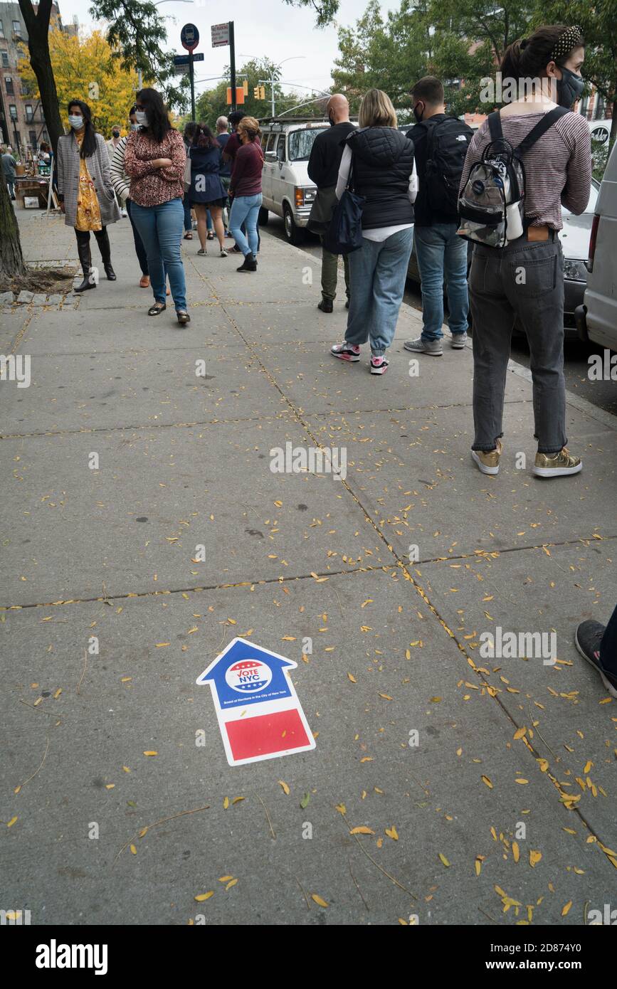 Die Leute standen auf der Houston Street in Soho für den ersten Tag der frühen Wahl des Staates New York bei den Präsidentschaftswahlen an. Ein Pfeil auf dem Bürgersteig poin Stockfoto
