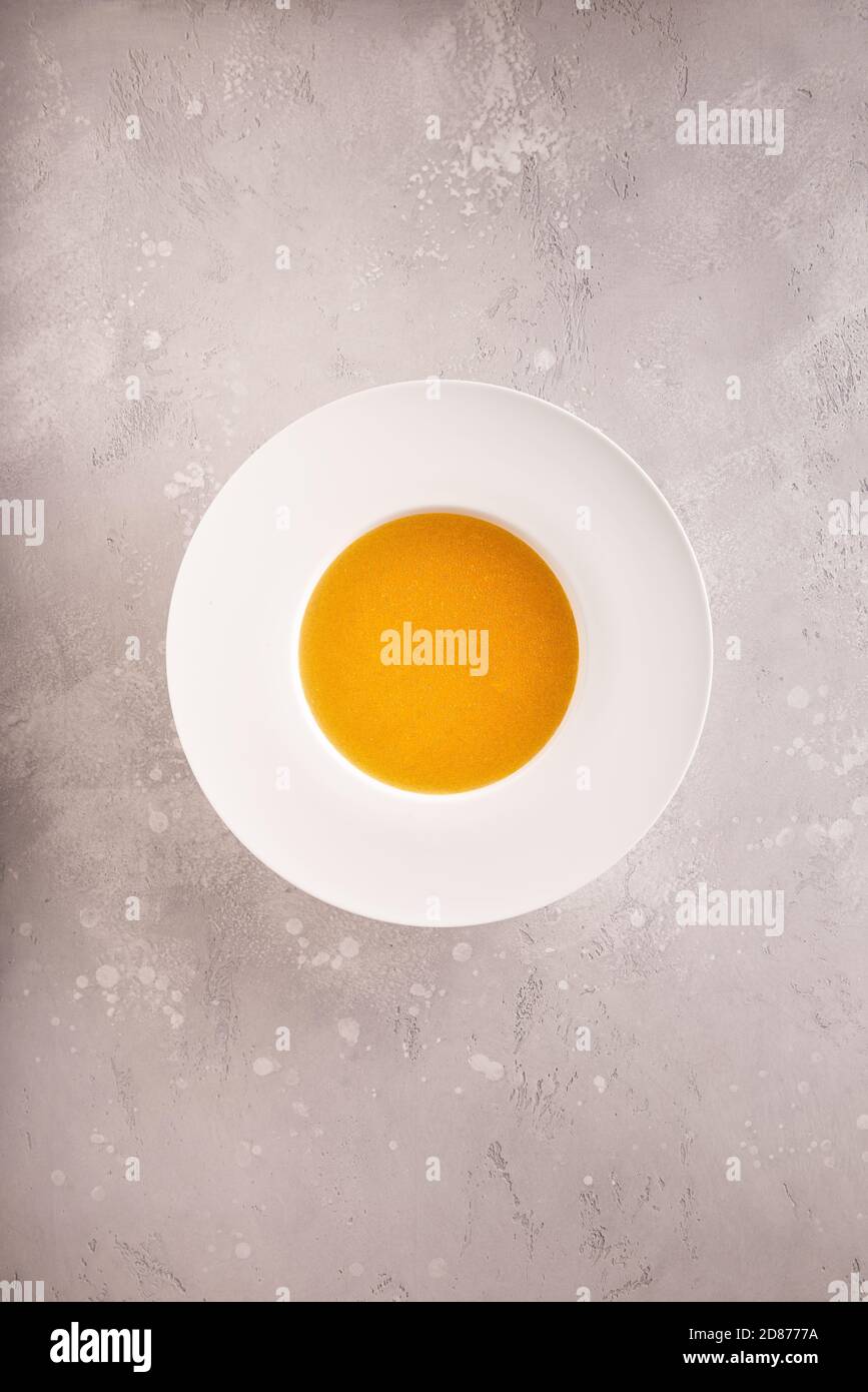 Klare hausgemachte Bouillon in großen weißen Suppenteller in der Mitte der grauen Stein Tischfläche. Direkt über der Ansicht. Vertikaler Hintergrund mit Kopierbereich. Hea Stockfoto