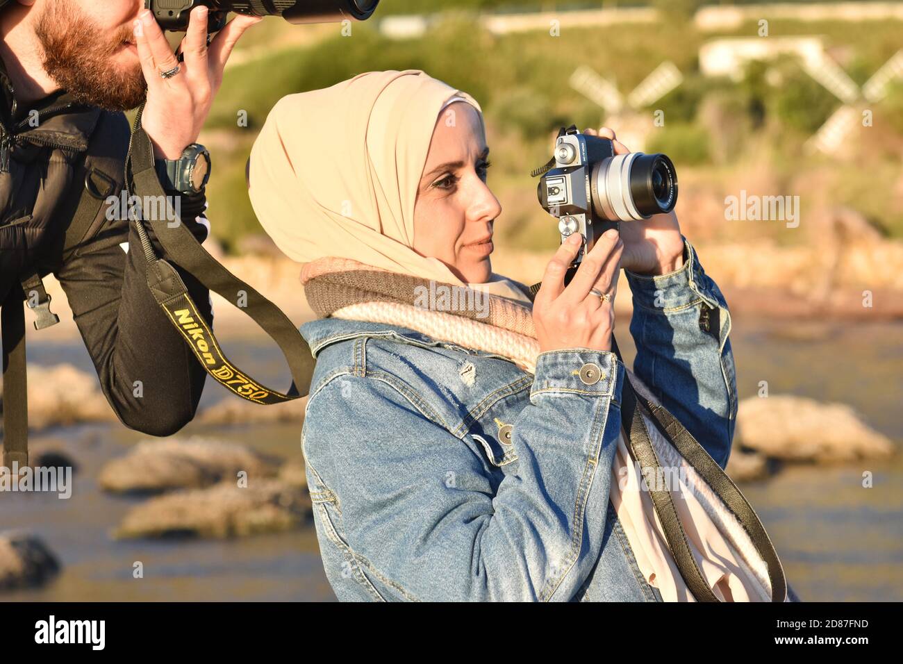 muslimischer Fotograf in Hijab, hält die Kamera und schaut hinein. Stockfoto