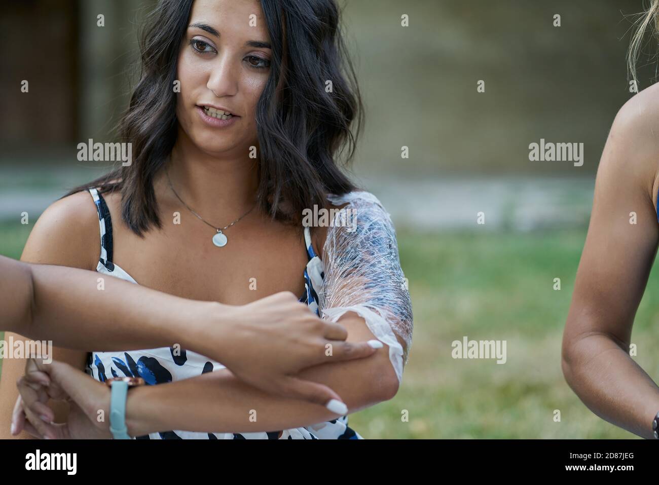 Frau zeigt ihr frisch gemachtes Tattoo eingewickelt in Kunststoff Ein Park Stockfoto