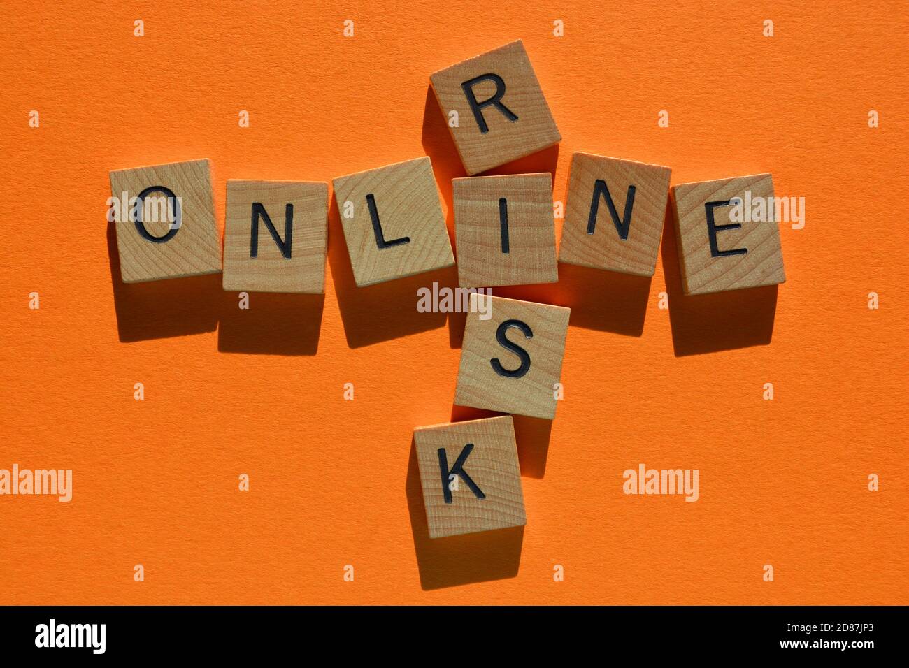 Online, Risiko, Wörter in Holzalphabet Buchstaben in Kreuzworträtsel Form isoliert auf orangefarbenem Hintergrund Stockfoto