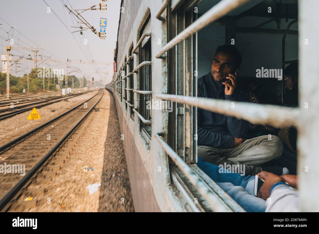 Junger Mann im Gespräch auf dem Handy, während pendeln von Neu-Delhi nach Agra, Sleeper Class Zug. Stockfoto