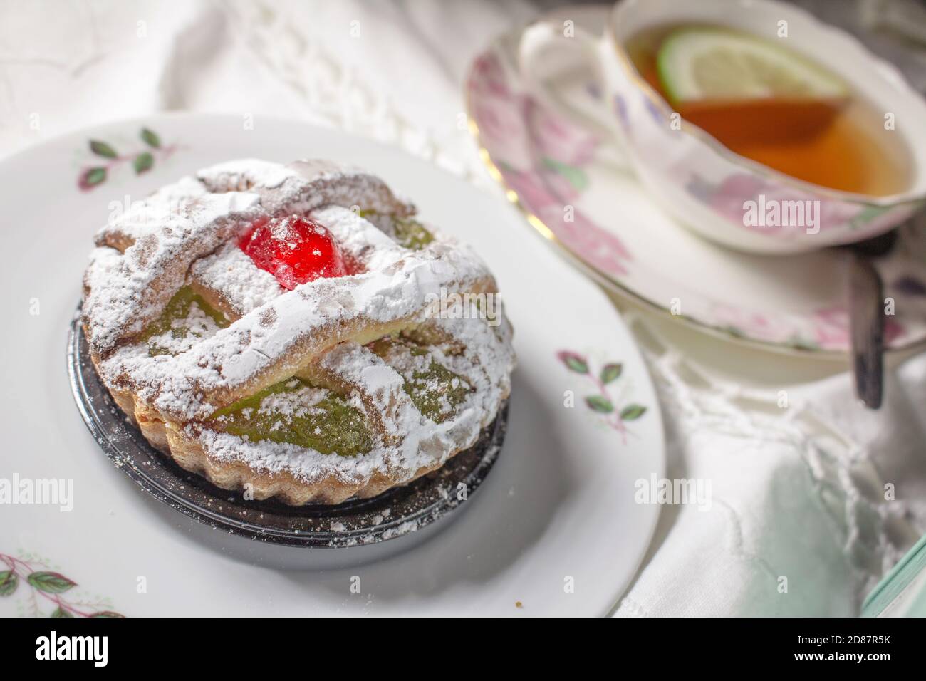 Eine besondere Süßigkeit aus Palermo namens 'Maria Stuarda', eine kleine Tarte mit sizilianischer Kürbismarmelade und kandierter Kirsche und einer Tasse Tee Stockfoto