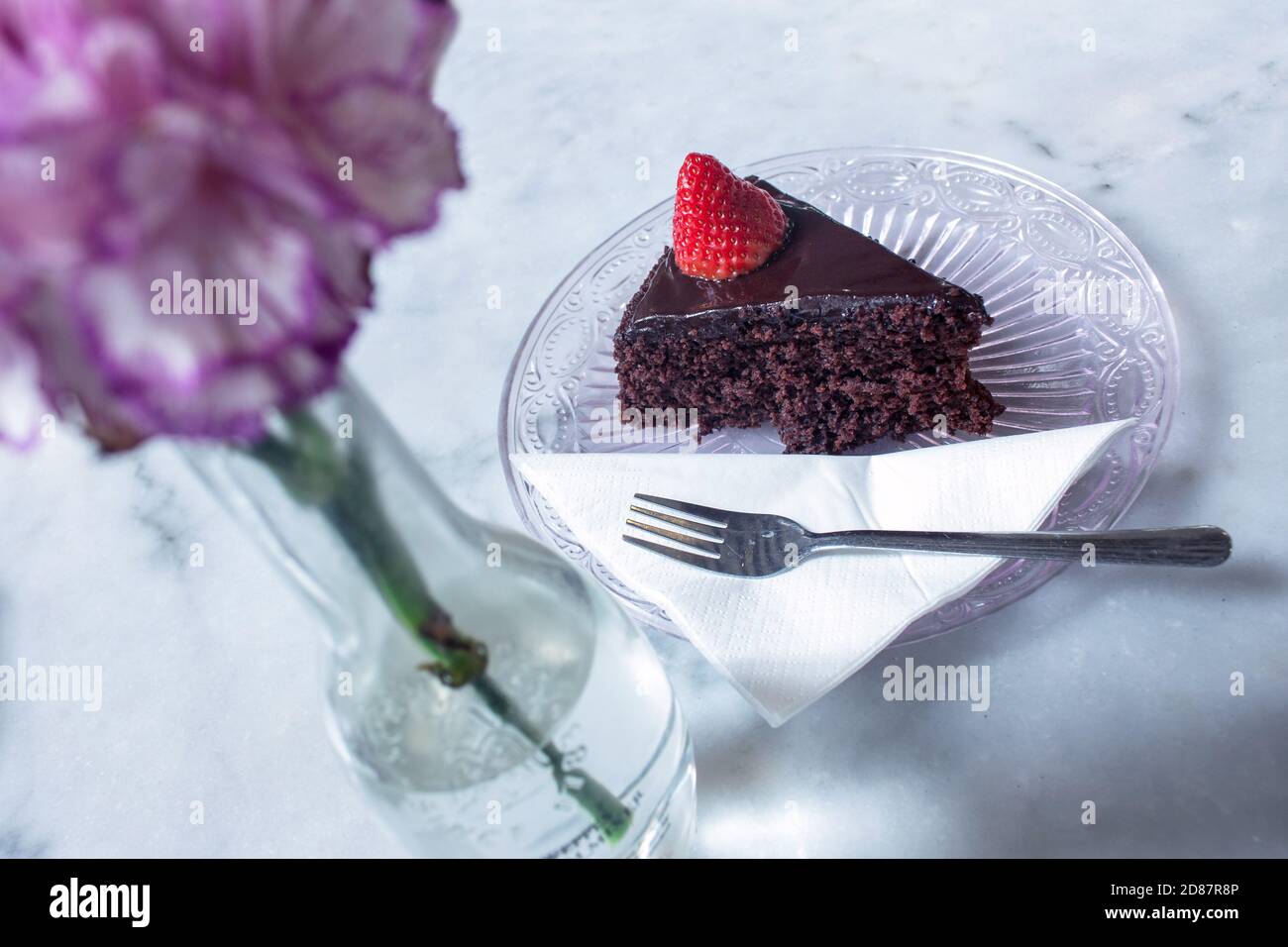 Top Schuss von einem leckeren Stück Schokoladenkuchen mit Erdbeere auf einer Glasuntertasse Stockfoto