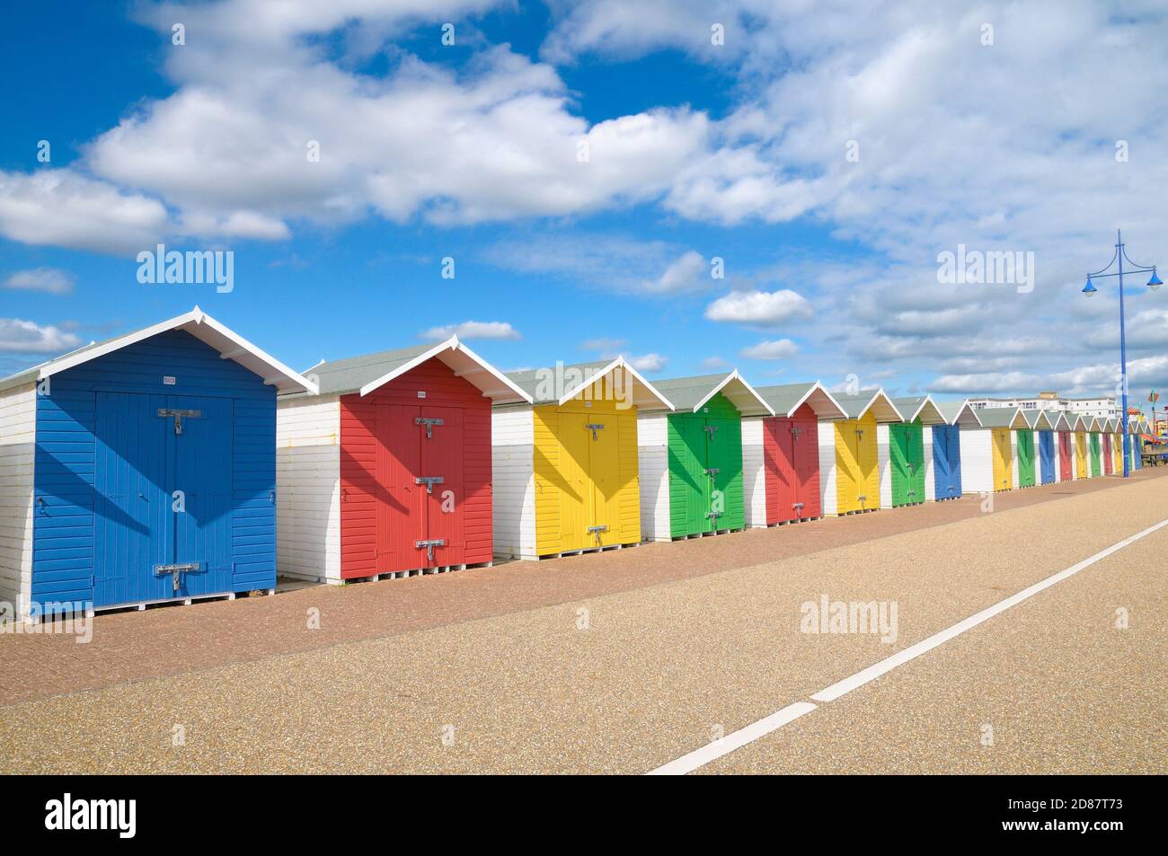 Eine Reihe von bunten hölzernen Strandhütten in strahlendem Sonnenschein mit blauem Himmel und Wolken, Eastbourne, East Sussex, England, Großbritannien Stockfoto
