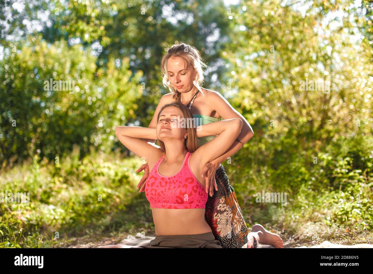 Expert Masseuse wendet ihre Massagefähigkeiten auf ihren Klienten im Sonnenlicht an. Stockfoto