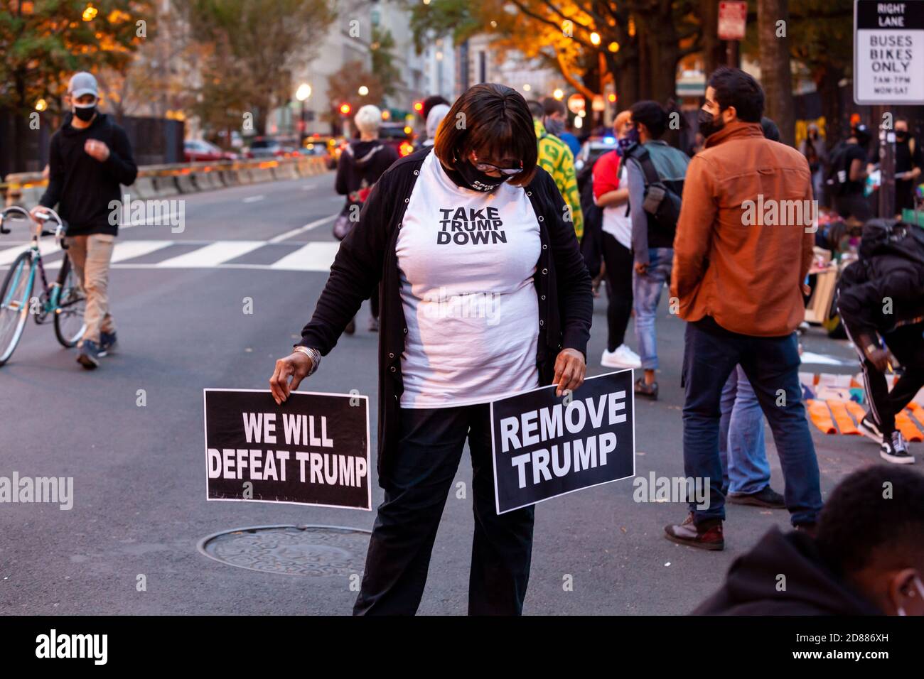 Washington, DC, USA, 27. Oktober 2020. Im Bild: Eine Frau stand bei einer Veranstaltung, bei der der Lafayette-Platz-Zaun mit Protestkunst vor dem Weißen Haus umgestaltet wurde, am Verkehr mit Schildern gegen Trump. Trump-Anhänger zerstörten die bestehende Kunst in der Nacht des 26. Oktober 2020, DC Polizisten beobachtet,. Der Zaun ist mit Protestkunst bedeckt, seit er während der Proteste nach George Floyds Tod hochging. Kredit: Allison Bailey/Alamy Live Nachrichten Stockfoto