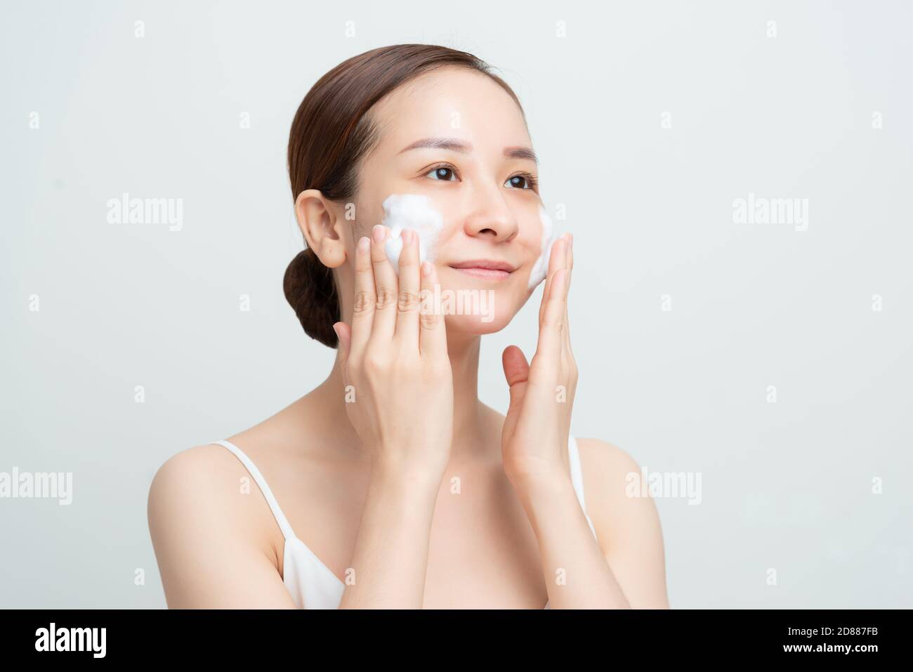 Hautpflege im Gesicht. Frau Anwendung Gesichtsreiniger auf Gesicht Nahaufnahme. Mädchen mit reinigenden kosmetischen Produkt auf der Haut, Waschen Gesicht auf hellen Hintergrund Stockfoto