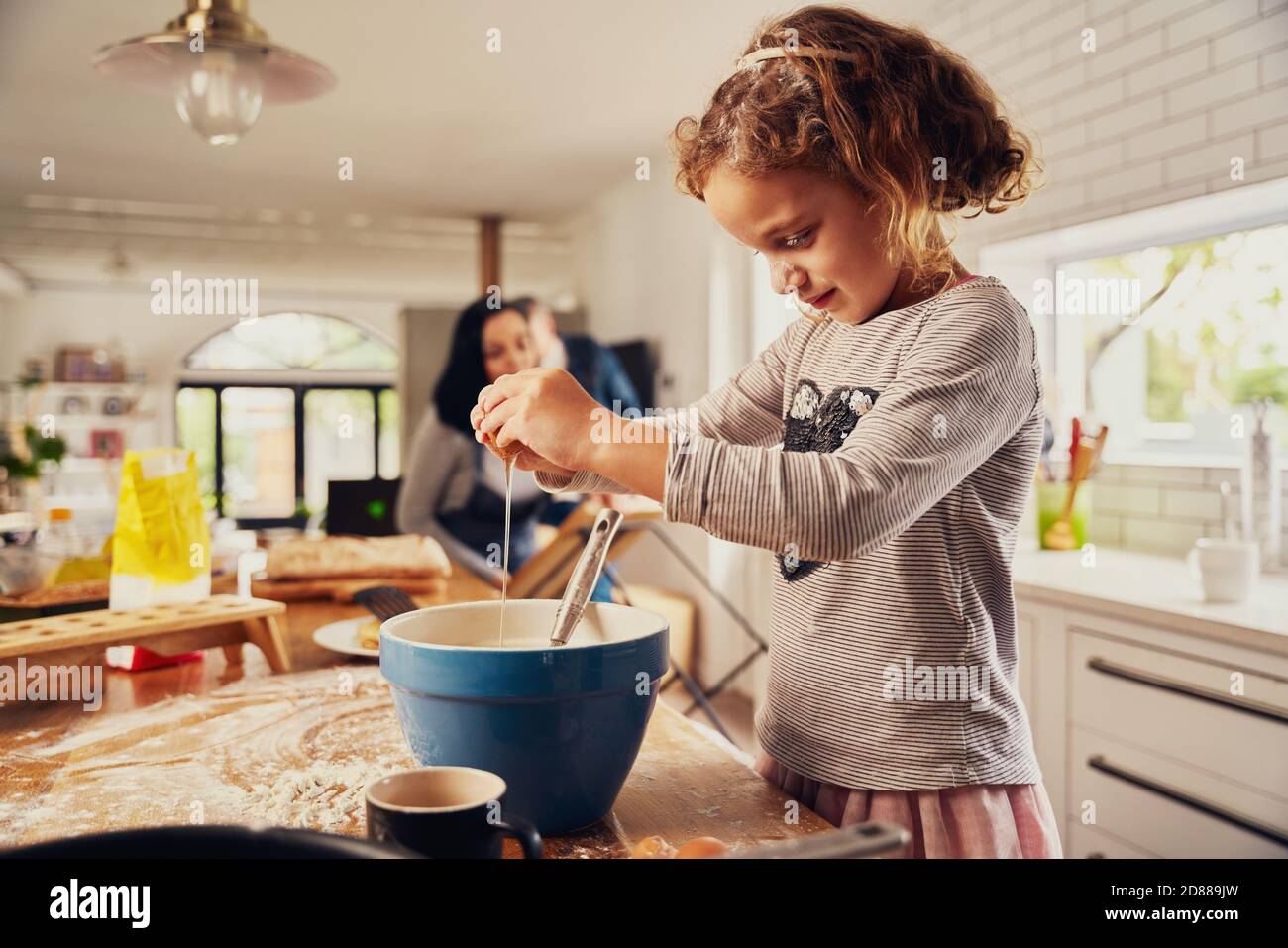 Nettes kleines Mädchen Kind brechen Ei in einer Schüssel, während Bereiten Teig in chaotische Küche Zähler zu Hause Stockfoto