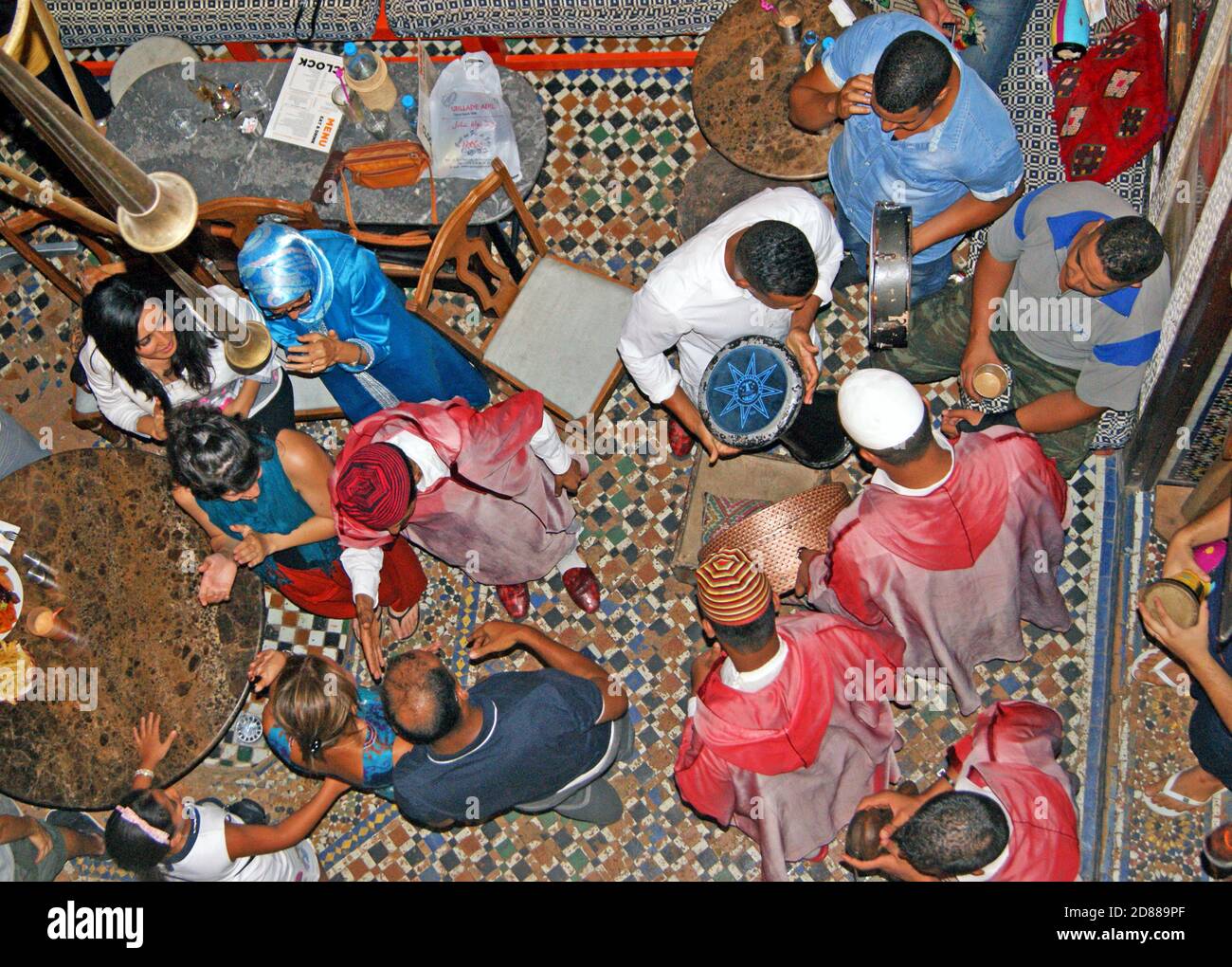 Ein Blick von oben auf die interkulturellen Interaktionen unten im Café Clock in Fès, Marokko, wo Musiker, Einheimische und Touristen zusammenkommen. Stockfoto