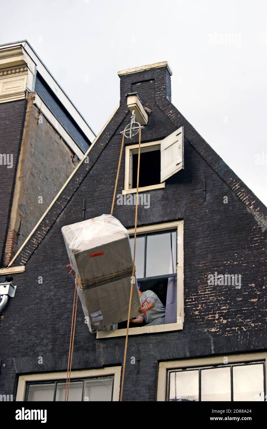 Eine Serie von Fotos zeigt das Heben von Möbeln in die obere Etage eines Kanalhauses in Amsterdam, Holland, wo Outdoor-Riemenscheibenlift-System verwendet wird. Stockfoto