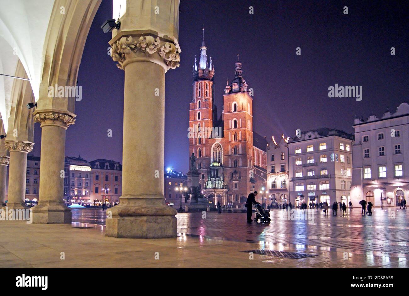 Die Abendlichter reflektieren historische Wahrzeichen auf dem regengetränkten Altstädter Platz in Krakau, Polen, am 10. Januar 2010. Stockfoto