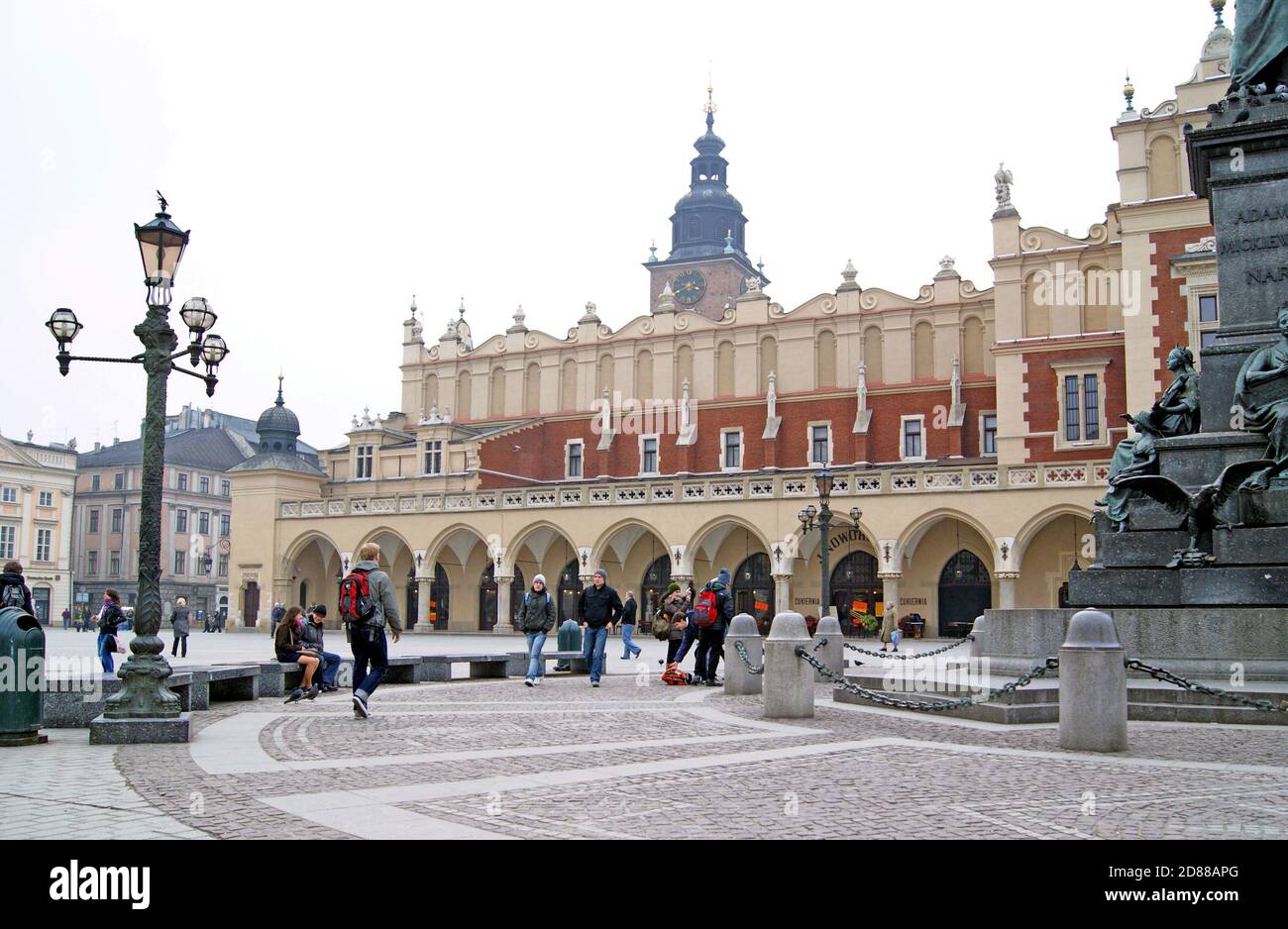 Der mittelalterliche Stadtplatz aus dem 13th. Jahrhundert in Krakau, Polen, umfasst den Tuchsaal, den Rathausturm im Hintergrund und das Adam-Mickiewicz-Denkmal. Stockfoto