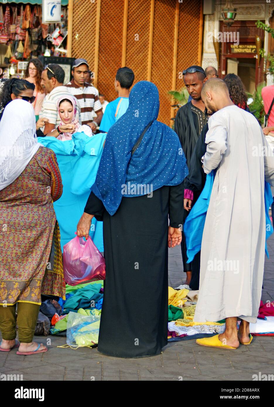 Händler und Kunden handeln auf der Straße in der Altstadt von Fez, Marokko, um Kleidung. Stockfoto