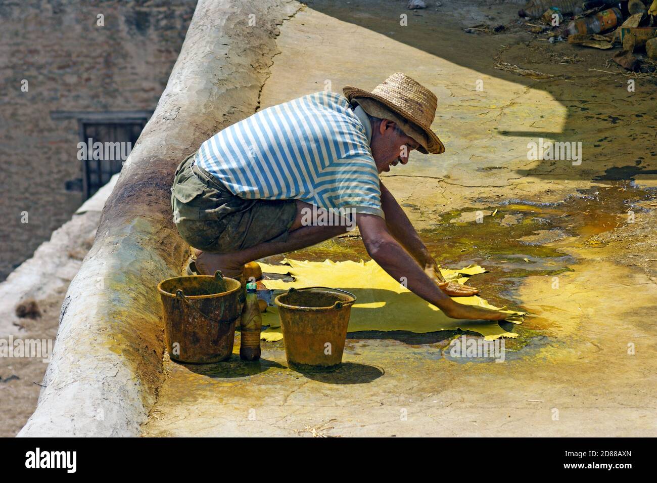 Ein älterer Mann verarbeitet in der Chouara-Gerberei in Fez, Marokko, gelben Farbstoff in den verarbeiteten Rohrohstoff. Stockfoto