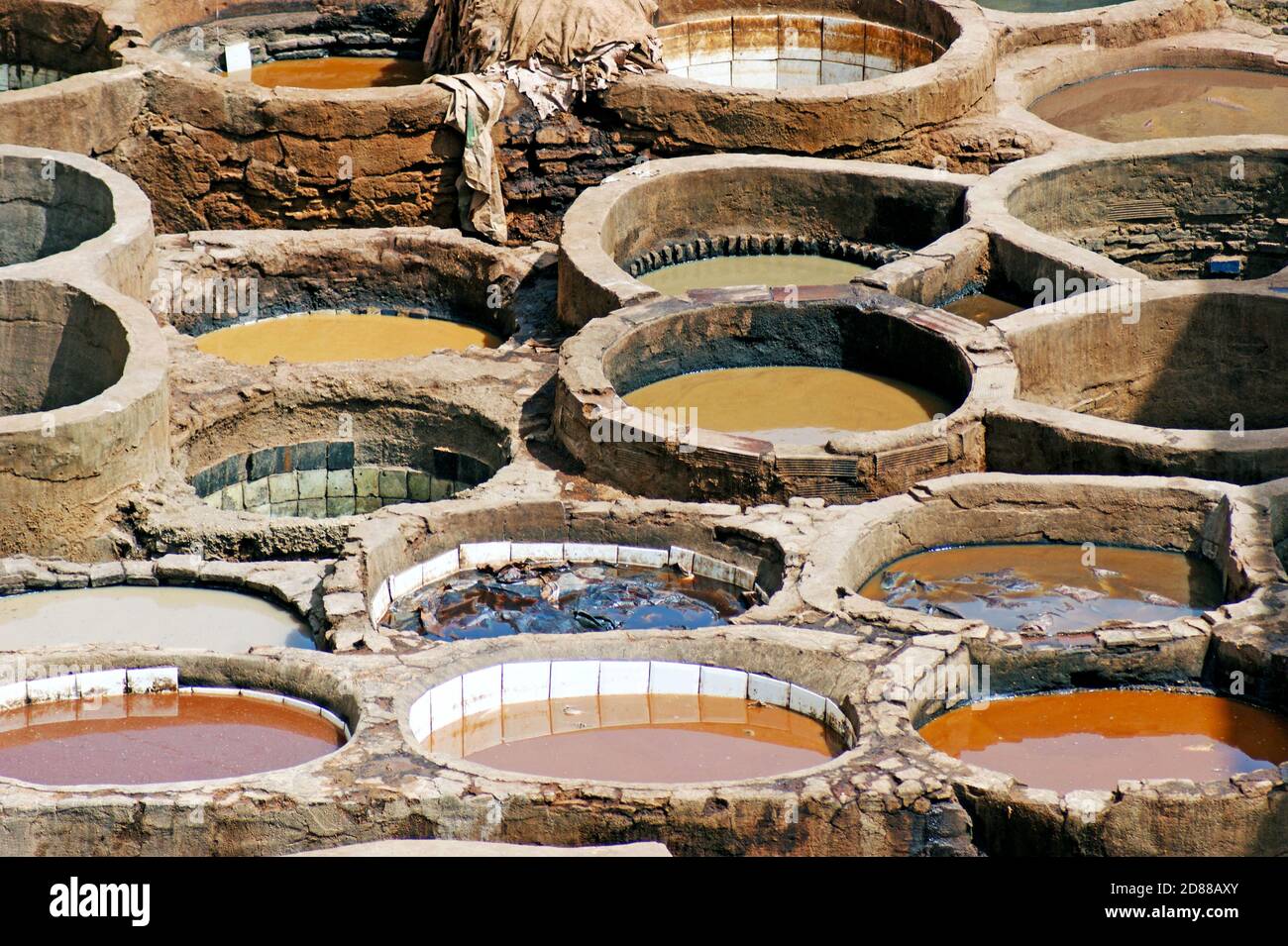 Historische runde Steinbottiche gefüllt mit natürlichen Farbstoffen in der größten und ältesten Gerberei in Fez, Medina, in der handgefertigte Lederherstellung stattfindet. Stockfoto