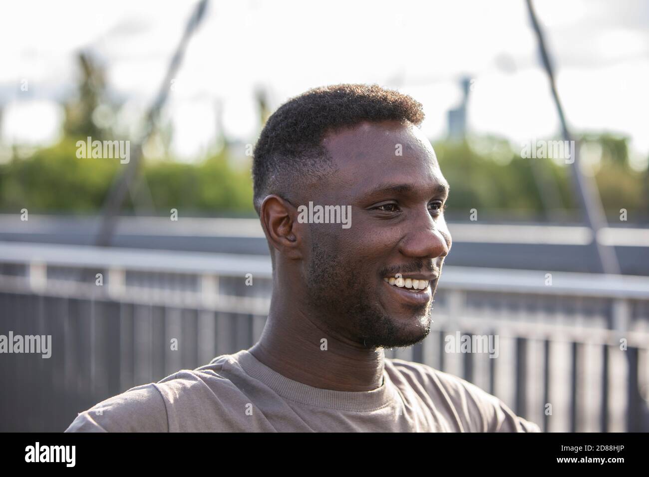 Junger afrikanischer Ethnie Mann lächelt im Freien. Seitenansicht. Hochformat. Nahaufnahme. Über den Schultern. Stockfoto