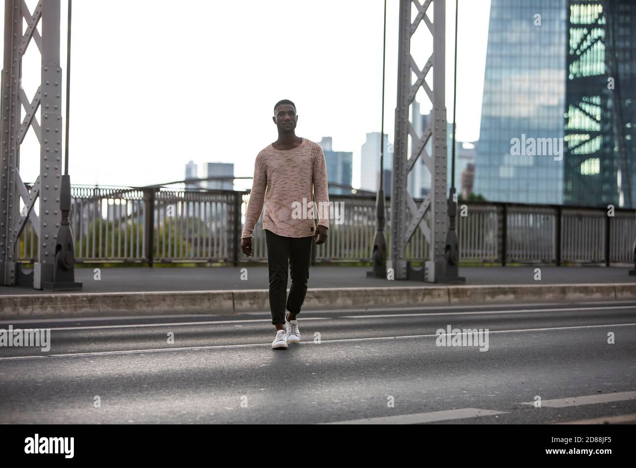 Selbstbewusster schwarzer Mann, der die Stadtstraße überquert. Lange Aufnahme. Vorderansicht. Stockfoto