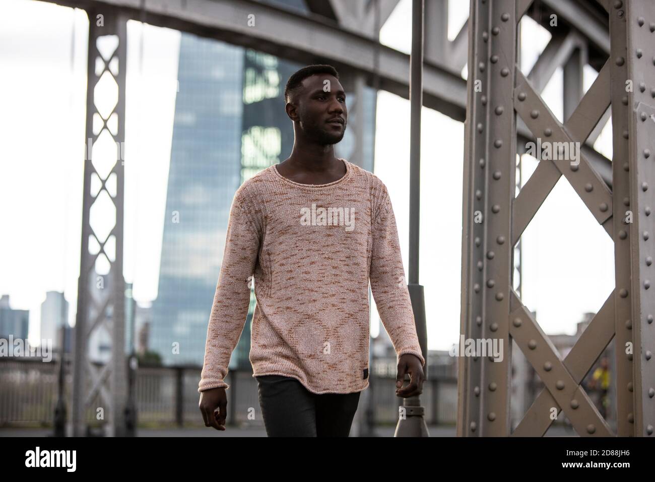 Modischer schwarzer Mann trägt Pullover zu Fuß selbstbewusst wegschauen. Dreiviertel Länge. Stockfoto