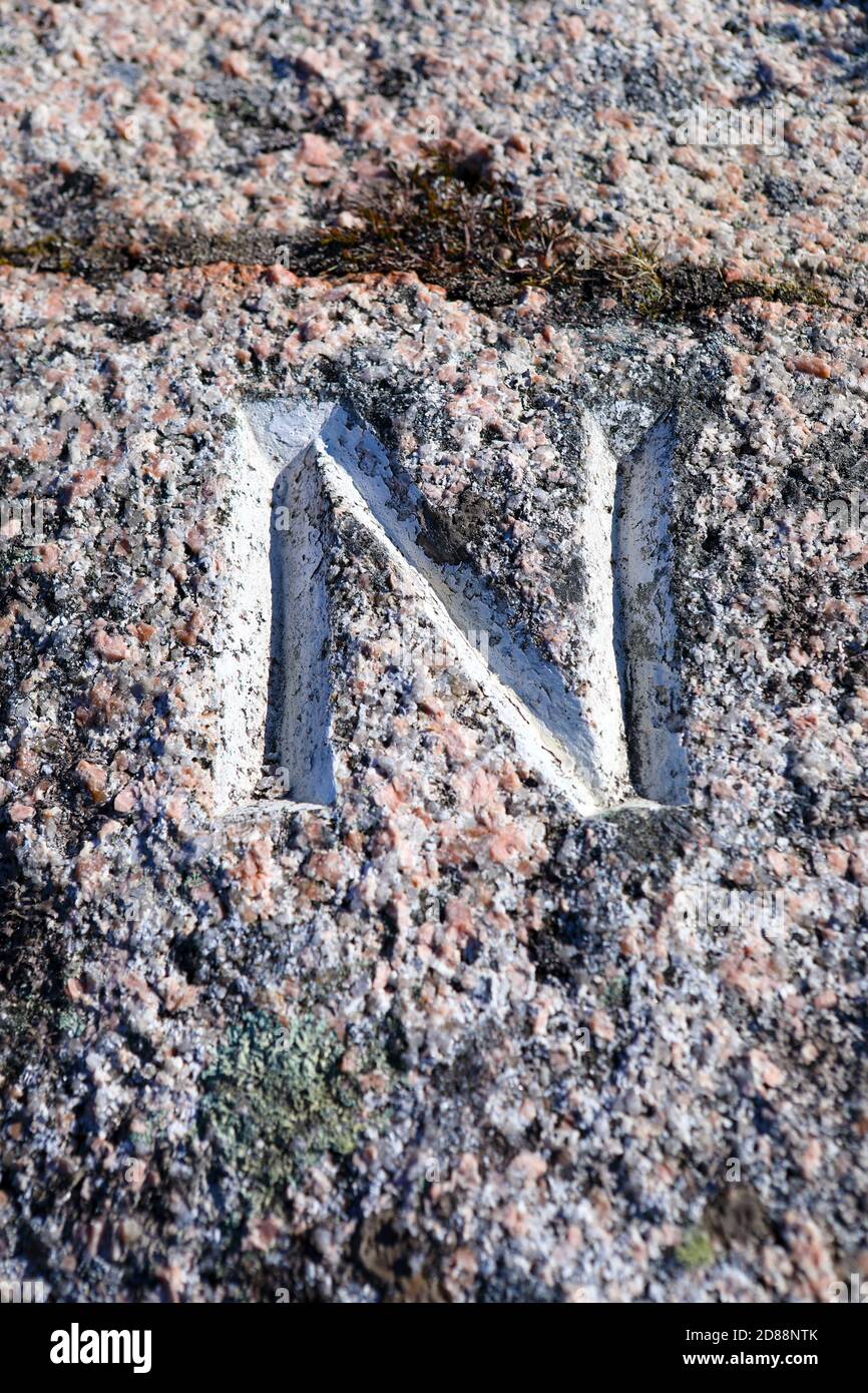 Der Buchstabe N, der die Richtung des Nordens angibt, wurde in einen rosafarbenen Granitfelsen an der Seite eines Pfades zur Traigh Gheal auf der Isle of Mull gehauen Stockfoto