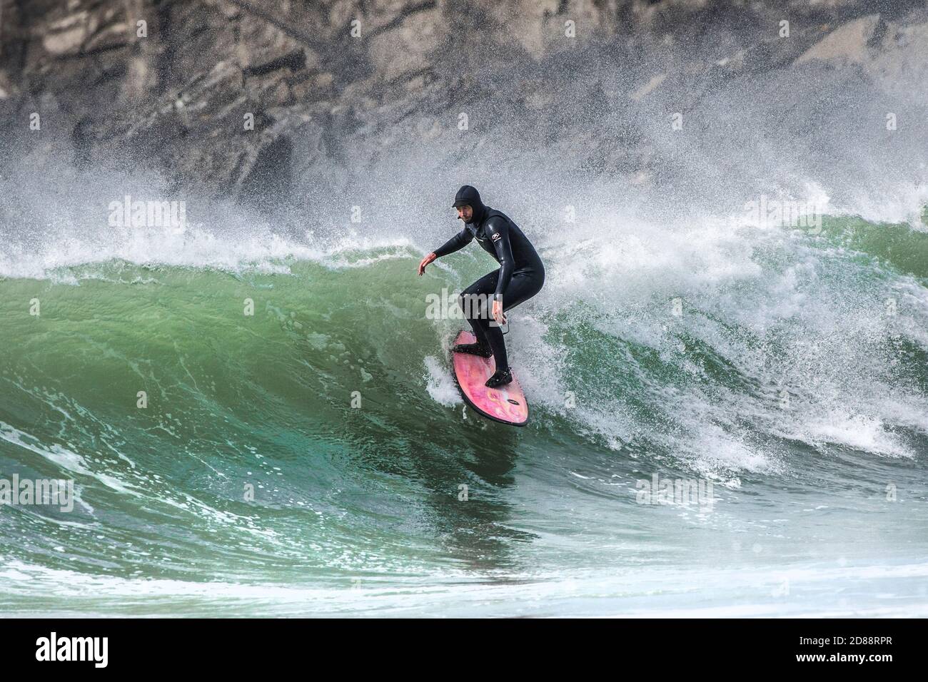 Spektakuläre Action als entschlossener männlicher Surfer reitet eine Welle bei Fistral in Newquay in Cornwall. Stockfoto