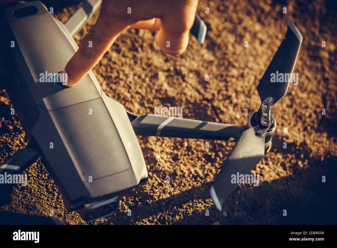Nahaufnahme einer Drohne auf dem Boden mit einer Hand, die sie berührt. Stockfoto