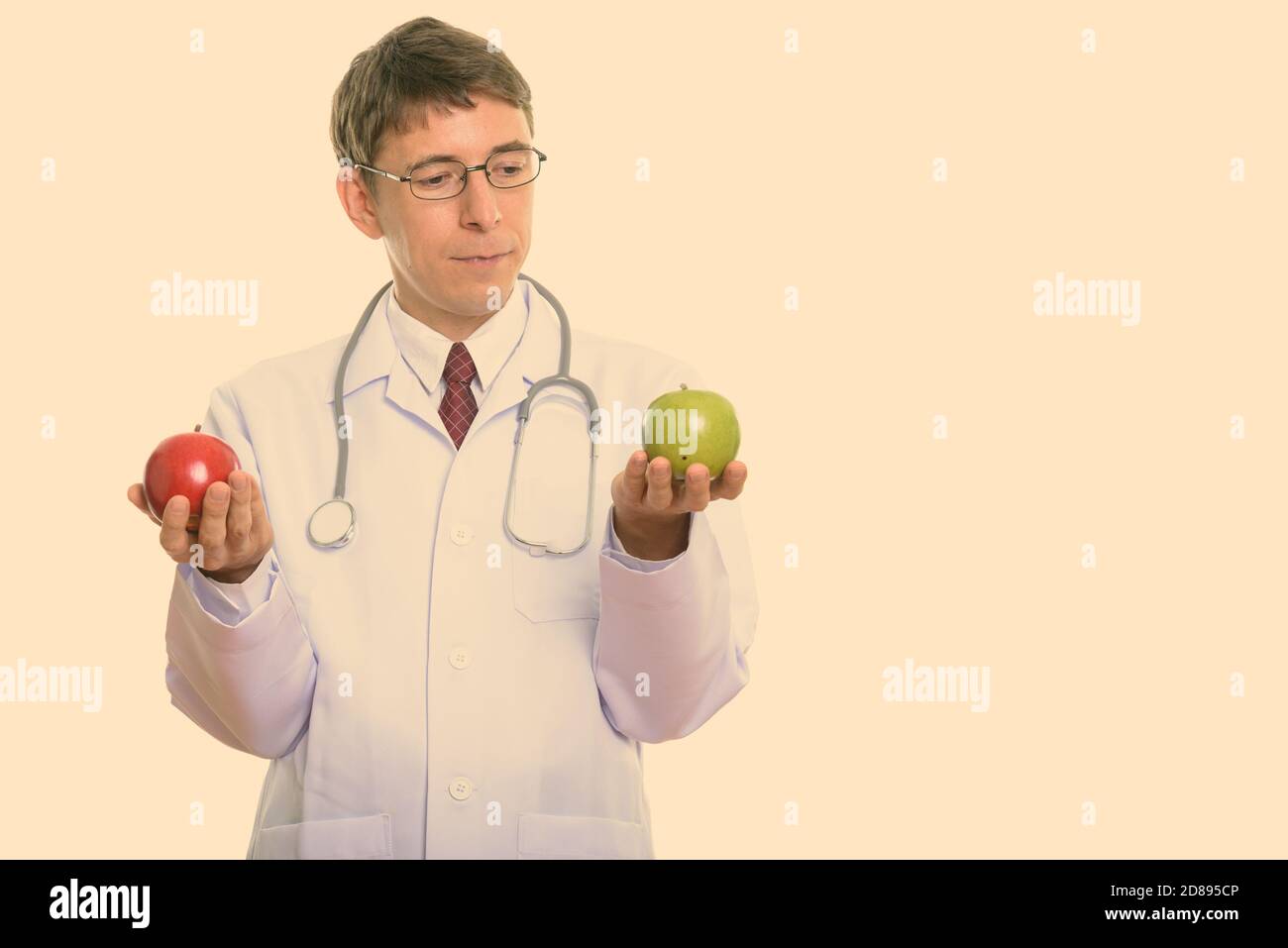 Studio Schuss von Mann Doktor, der zwischen rotem apfel und grünem apfel wählt Stockfoto