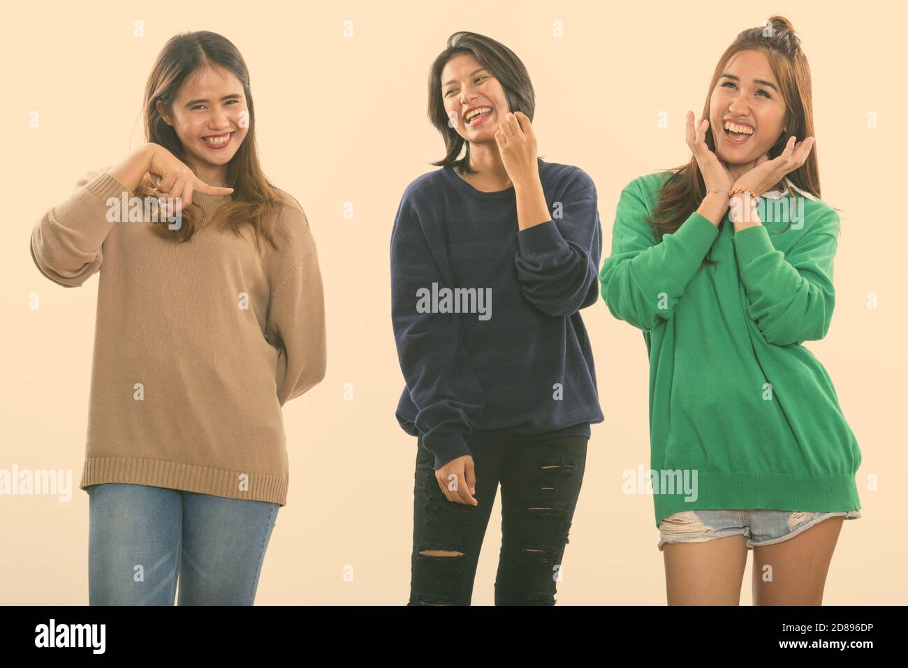 Drei glückliche junge asiatische Frau Freunde lächelnd und lustige Gesichter zusammen mit einem Freund Zeigefinger Stockfoto