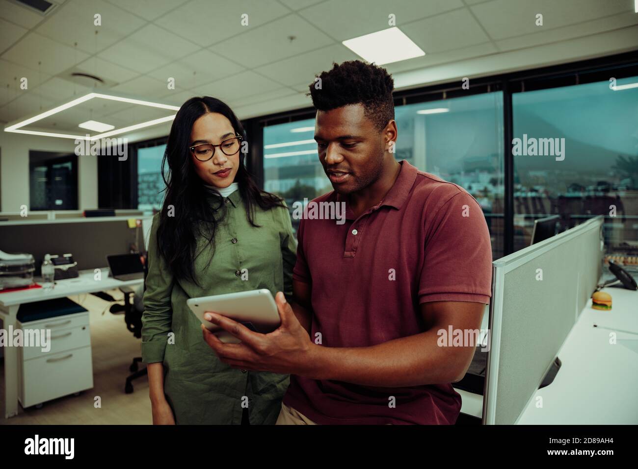 Multiethnische Partner, die Geschäftsberichte über ein digitales Tablet einreichen Bürogebäude Stockfoto