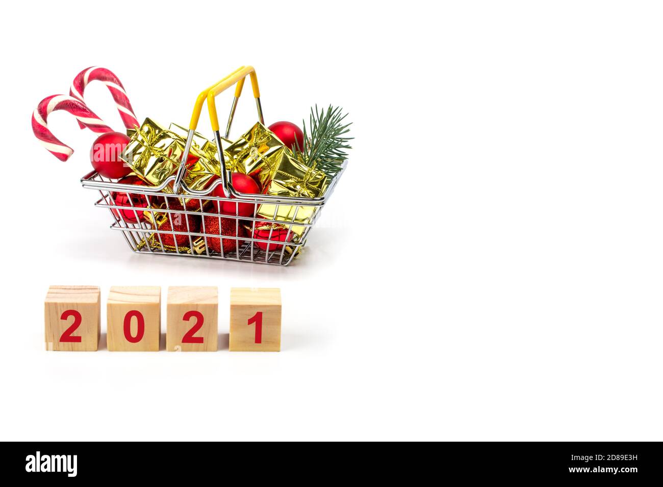 Kleiner Lebensmittelkorb gefüllt mit Weihnachtsgeschenken isoliert auf weißem Hintergrund. Holzwürfel gelegt 2021 Text. Cristmas Einkaufskonzept. Copyspace Stockfoto