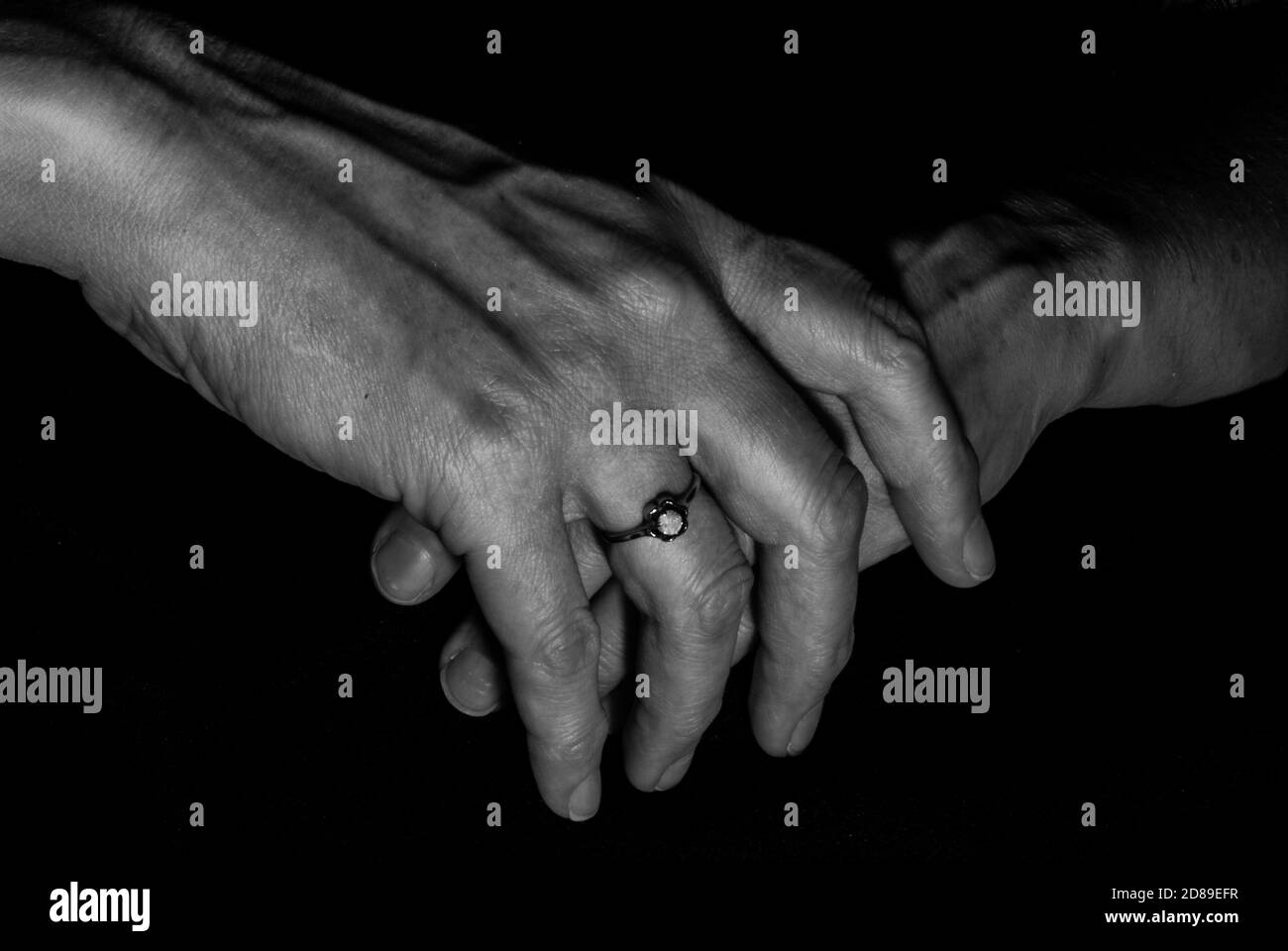 Schwarz-weißes Bild von weiblichen Händen zusammen mit geklammert Schwarzer Hintergrund Stockfoto